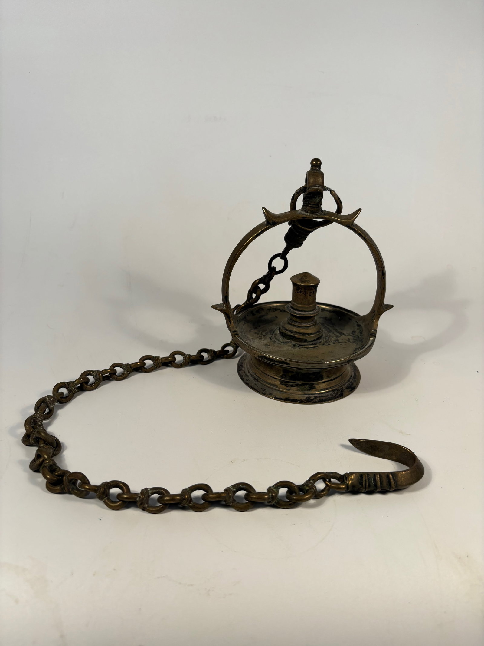 A Himalayan bronze oil lamp: Late 19th century, An antique bronze ritual oil lamp from the Himalayan region, likely Tibetan or Nepalese in origin. The lamp features a wide circular base, a central wick holder, and an arched handl