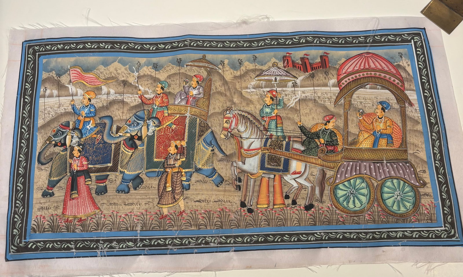 Indian Rajasthani Royal Wedding Procession Painting on Silk: A colorful hand-painted Indian Rajasthani miniature-style painting depicting an elaborate royal wedding or ceremonial procession. The scene features richly dressed noble figures traveling on decorated