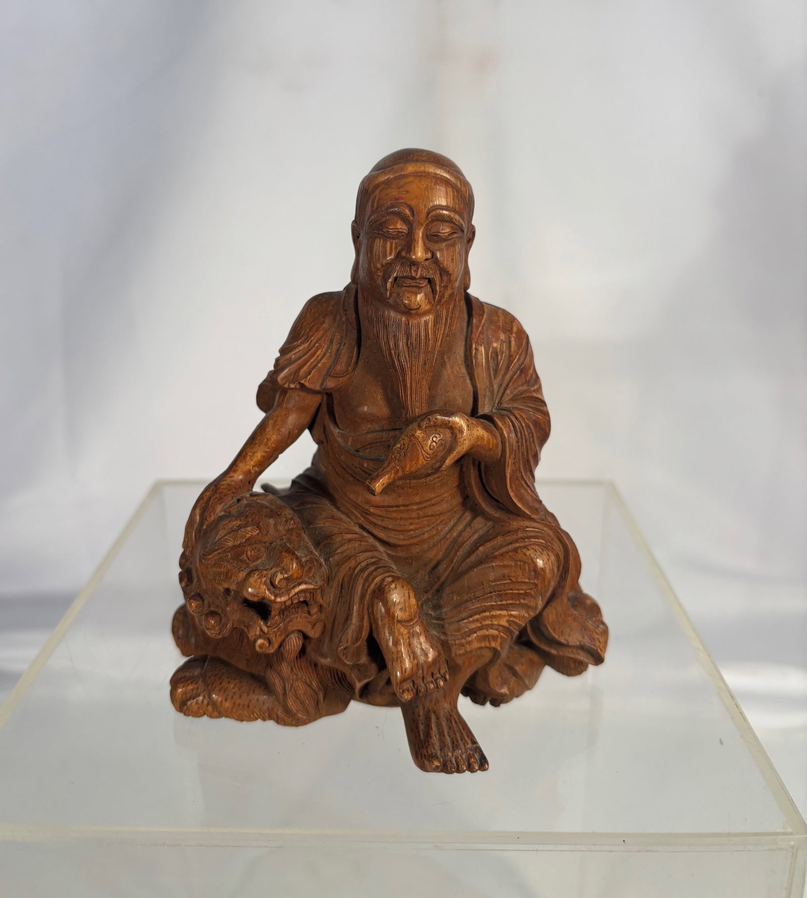 A Chinese Bamboo Root Carving Figure of Fuhu Luohan (The Tiger-Taming Arhat): Chinese bamboo root carving depicting Fuhu Luohan seated beside a tiger. The arhat is shown holding a gourd and dressed in flowing robes, with the tiger resting submissively at his side. The sculpture