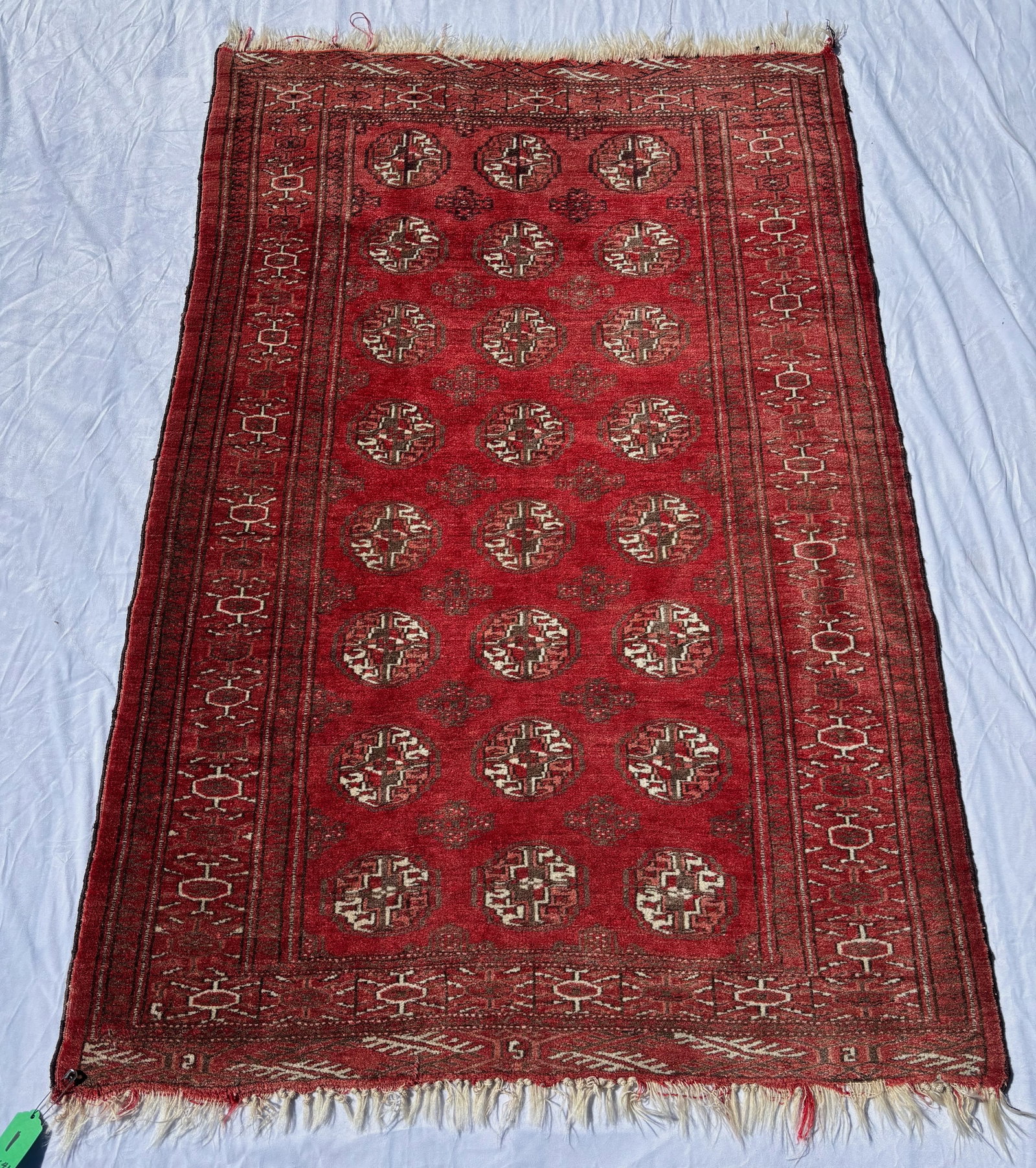 Pakistani Bokhara-Style Silky Wool Rug, 64 x 41 in.: Hand-knotted rug featuring repeating gul medallions on a rich red field within multiple geometric borders. Executed in red, burgundy, ivory, and brown tones with a soft silky wool pile and traditional