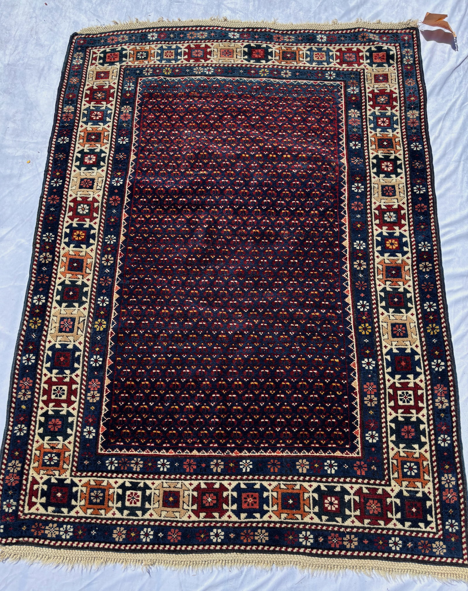 Caucasian Style Hand Knotted Wool Rug 58 x 49 in.: A Caucasian style hand knotted wool rug, featuring an allover geometric field within multiple stylized floral and geometric borders. Rendered in deep burgundy, navy, ivory, and soft earth tones with t