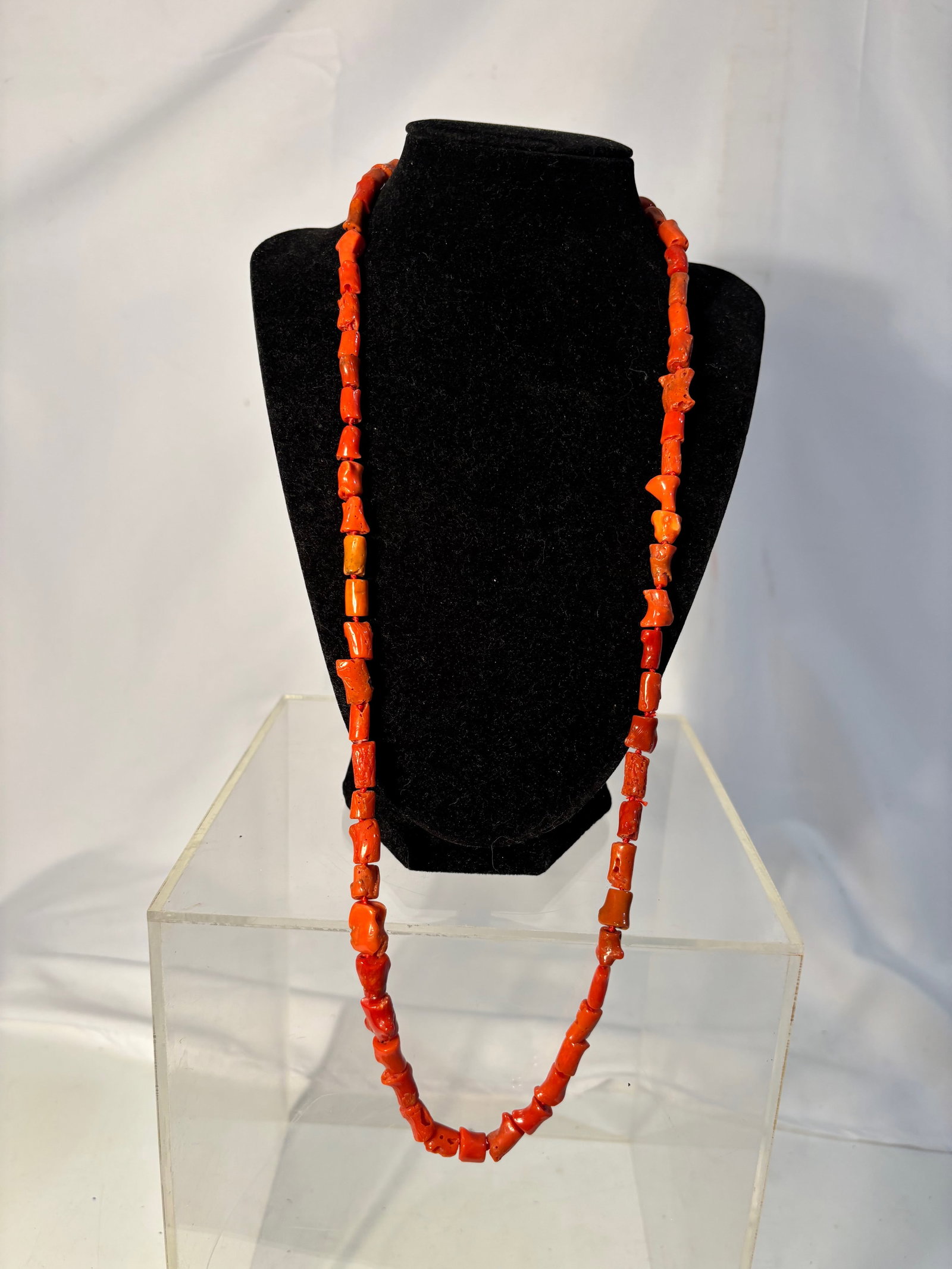 A Natural Red Coral Beaded Necklace, Irregular Branch Form: A necklace composed of natural red coral beads in irregular branch form. The beads display organic texture and variation in size and tone, characteristic of natural coral. Strung as a continuous stran