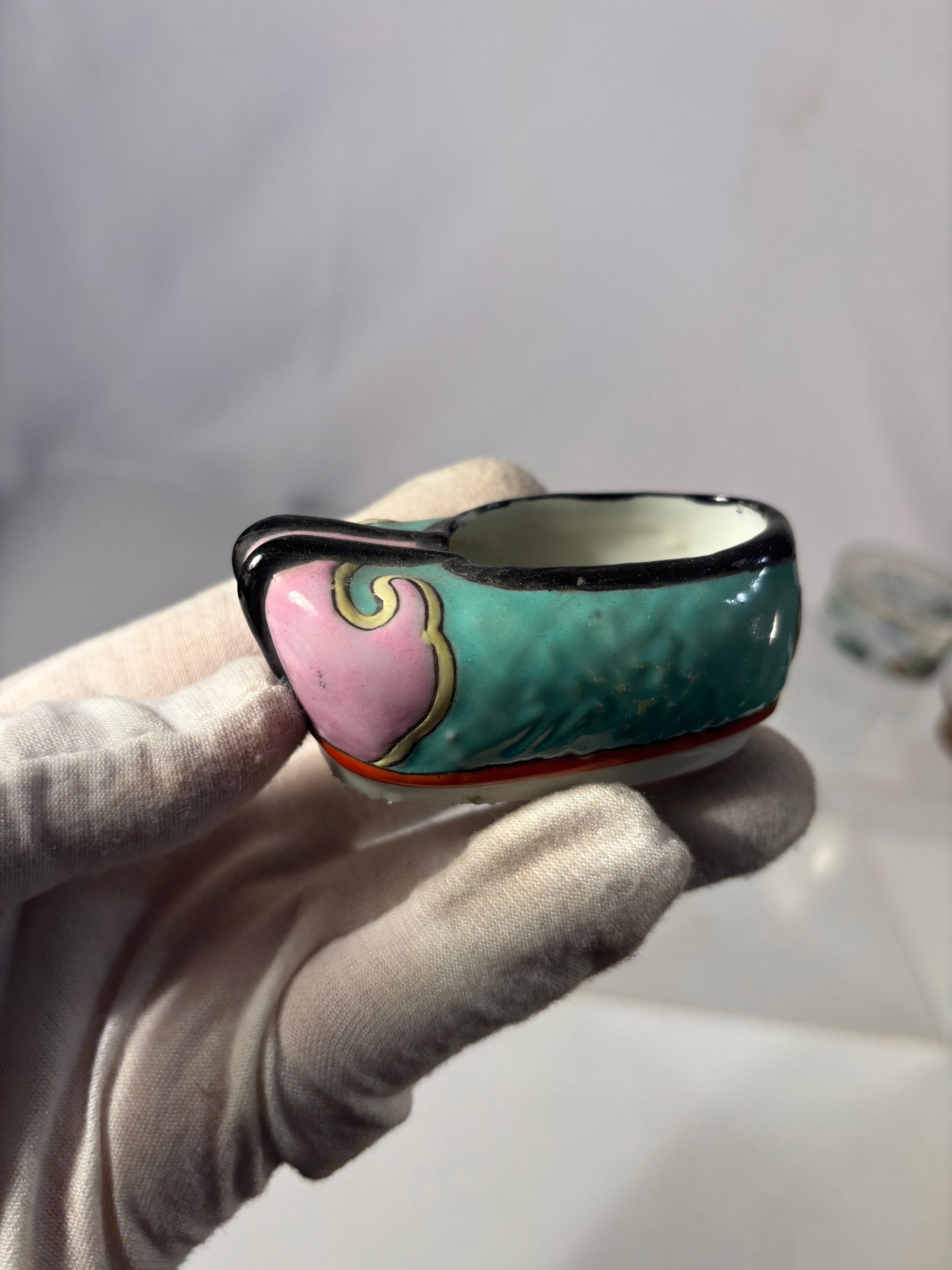 A Chinese Porcelain Shoe-Form Brush Washer: 19th–early 20th century); Chinese porcelain brush washer or small dish modeled in the form of a traditional shoe. Decorated in famille-rose style enamels with turquoise, pink, black, and gilt accent