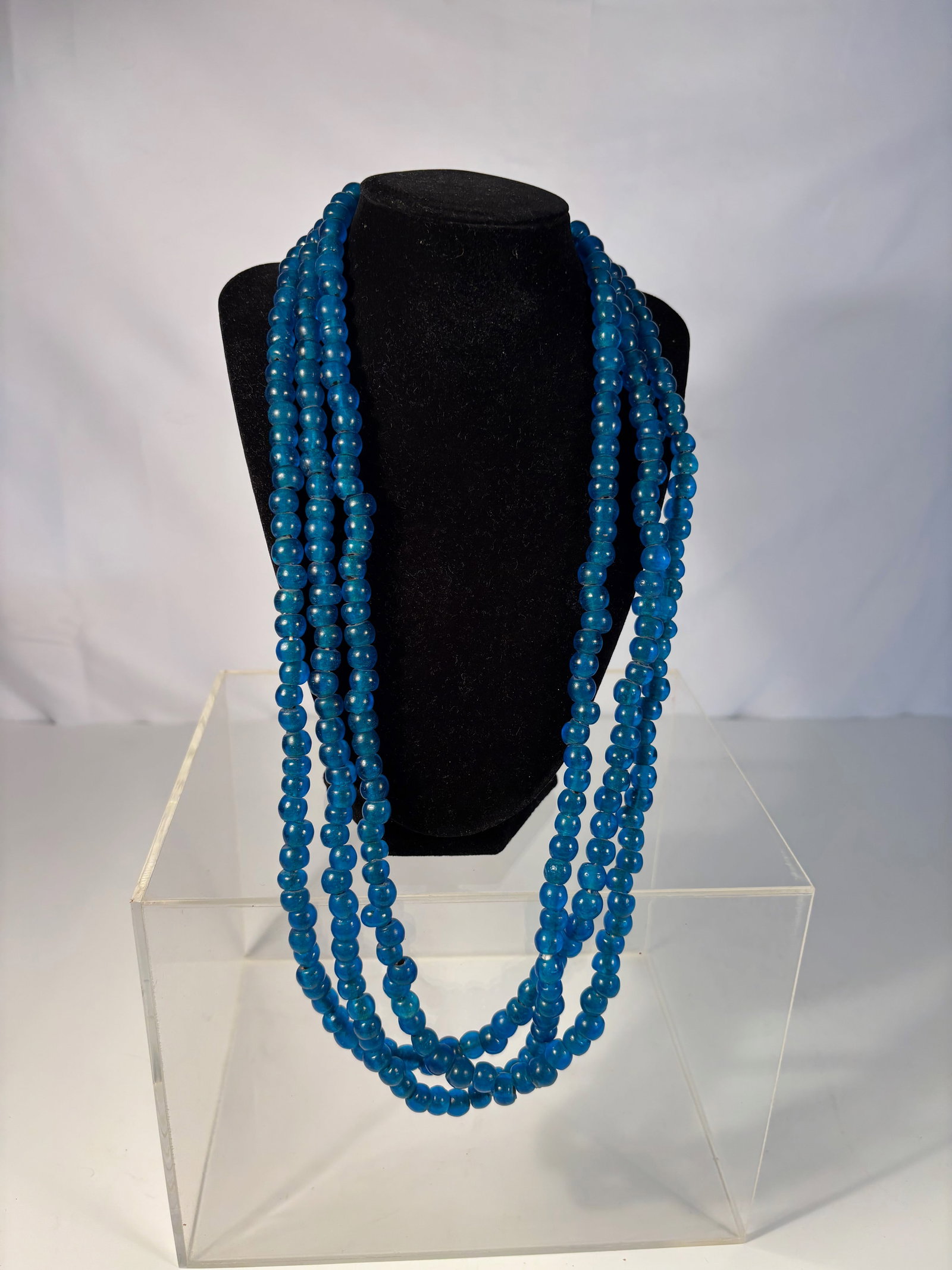 Three-Strand Blue Glass Bead Necklace: Three-strand necklace composed of vibrant cobalt-blue glass beads, each with a smooth polished surface and uniform rounded form. The strands are of graduated length, allowing for a layered drape when 