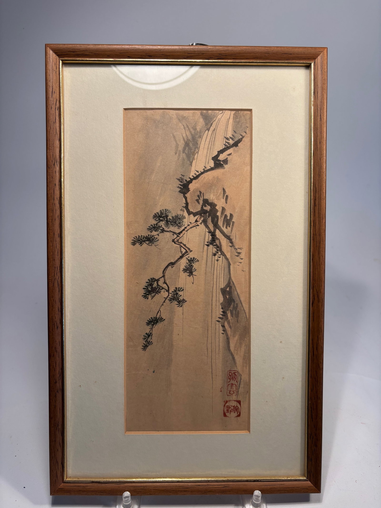 A Japanese Ink Painting of Pine and Waterfall with artist signature: Circa 1900 , A vertical ink-on-paper landscape painting depicting a pine tree growing from a rugged cliff with a cascading waterfall in the background. Executed in a literati (scholarly) style with ex