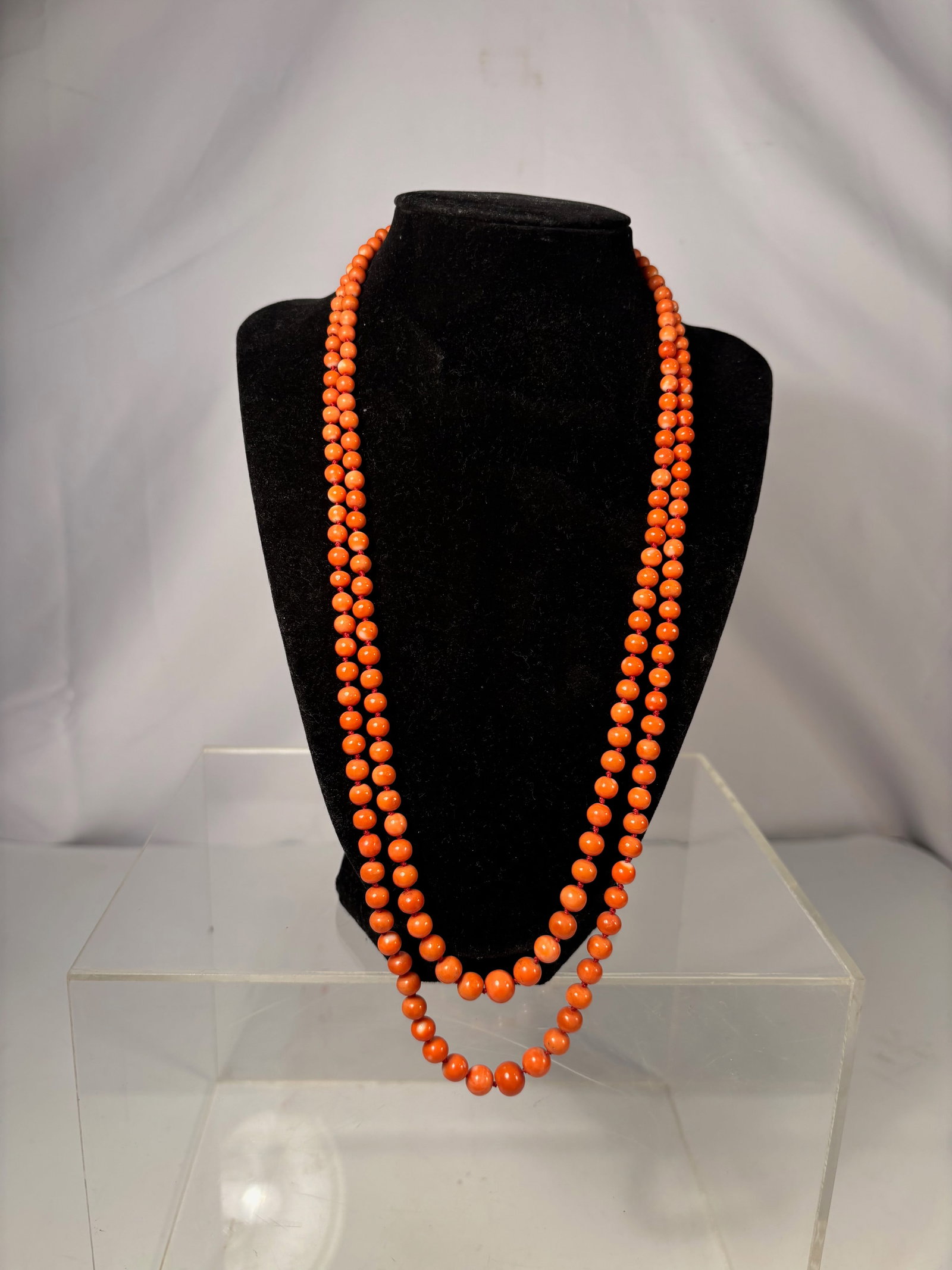 A Double-Strand Natural Coral Bead Necklace: Double-strand coral bead necklace composed of uniformly shaped round orange coral beads, individually hand-knotted between beads. The necklace is finished with a rectangular yellow metal box clasp (un