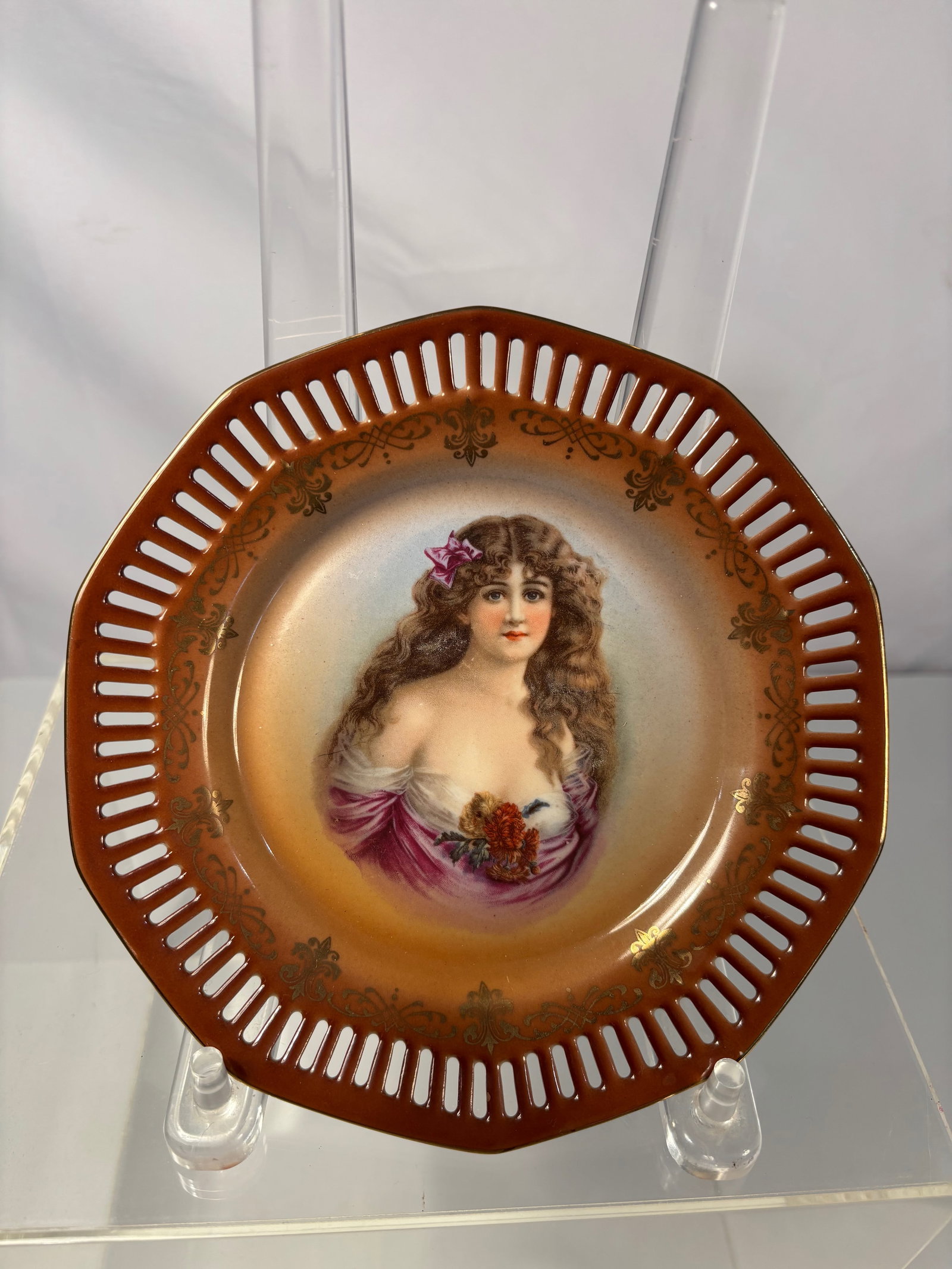 A Royal Vienna Style Hand-Painted Portrait Plate, Austria,: Late 19th Century; A fine Austrian porcelain cabinet plate, circa 1900, hand-painted with the portrait of a young beauty in off-the-shoulder drapery, adorned with a purple ribbon and holding flowers. 