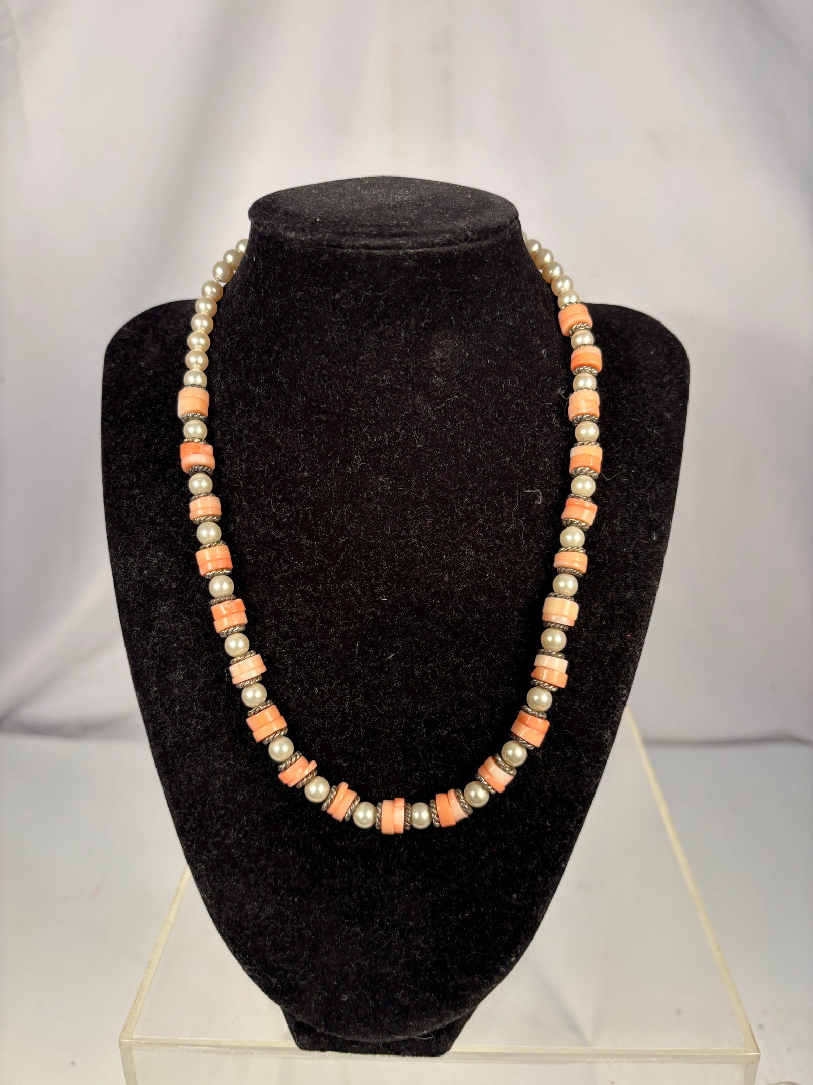 Vintage Pearl and Pink Coral Bead Necklace: A vintage single-strand necklace composed of cream-colored pearl beads and pink coral barrel-form beads, separated by decorative rhinestone-set spacers. Finished with a metal clasp. Length: 18 inches.