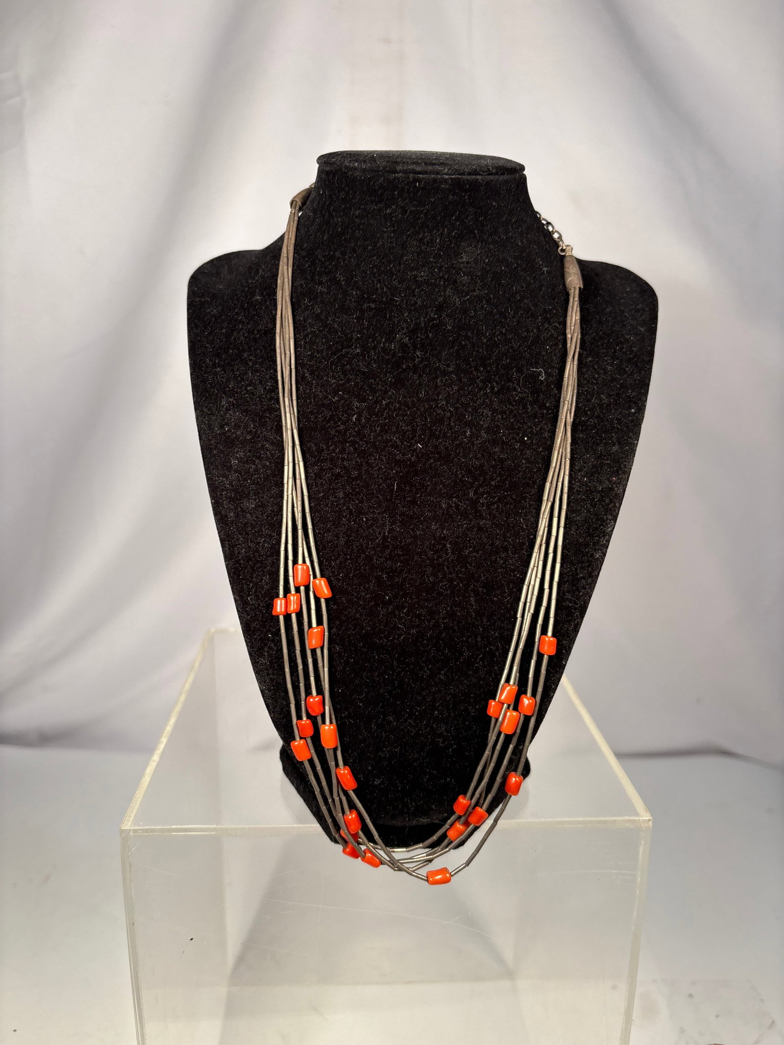 Vintage Multi-Strand Coral and Silver Tube Bead Necklace: A vintage multi-strand necklace composed of slender silver tube beads interspersed with polished orange-red coral barrel beads. Finished with elongated silver end caps, a hook clasp, and an adjustable