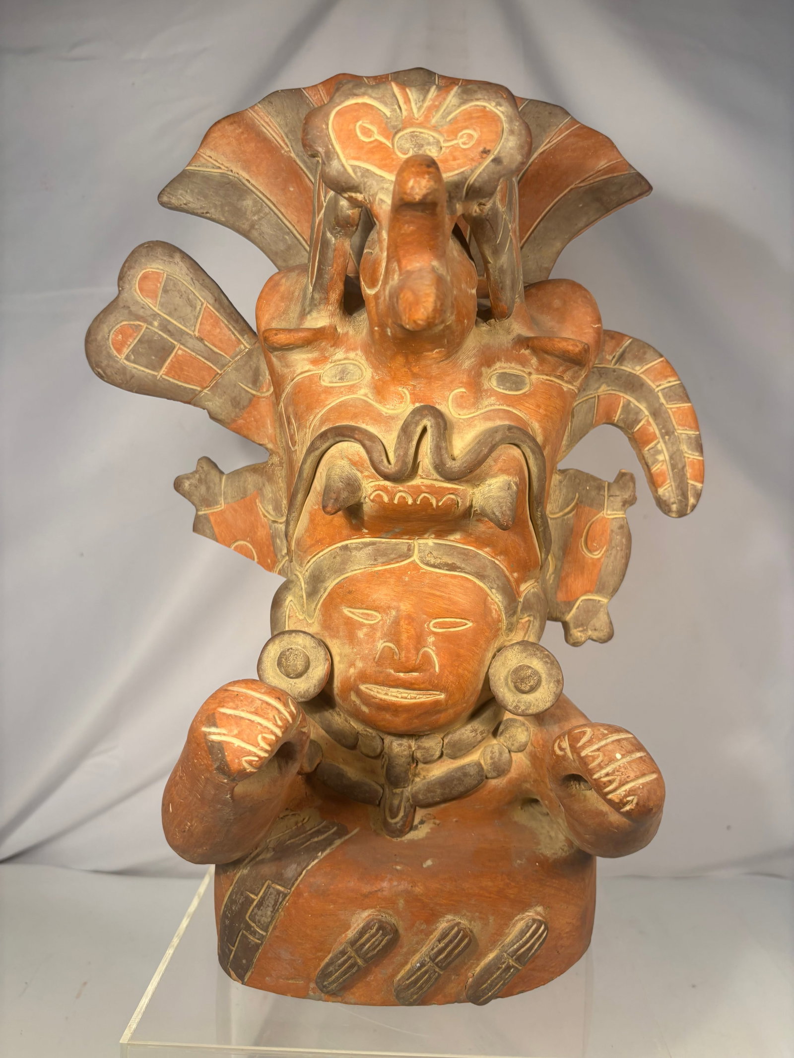 Large Pre-Columbian Style Polychrome Pottery Figural Whistle Vessel: A polychrome terracotta figural vessel modeled as a seated ceremonial figure wearing an elaborate zoomorphic headdress with projecting elements. The figure displays applied ear ornaments, necklace, ra