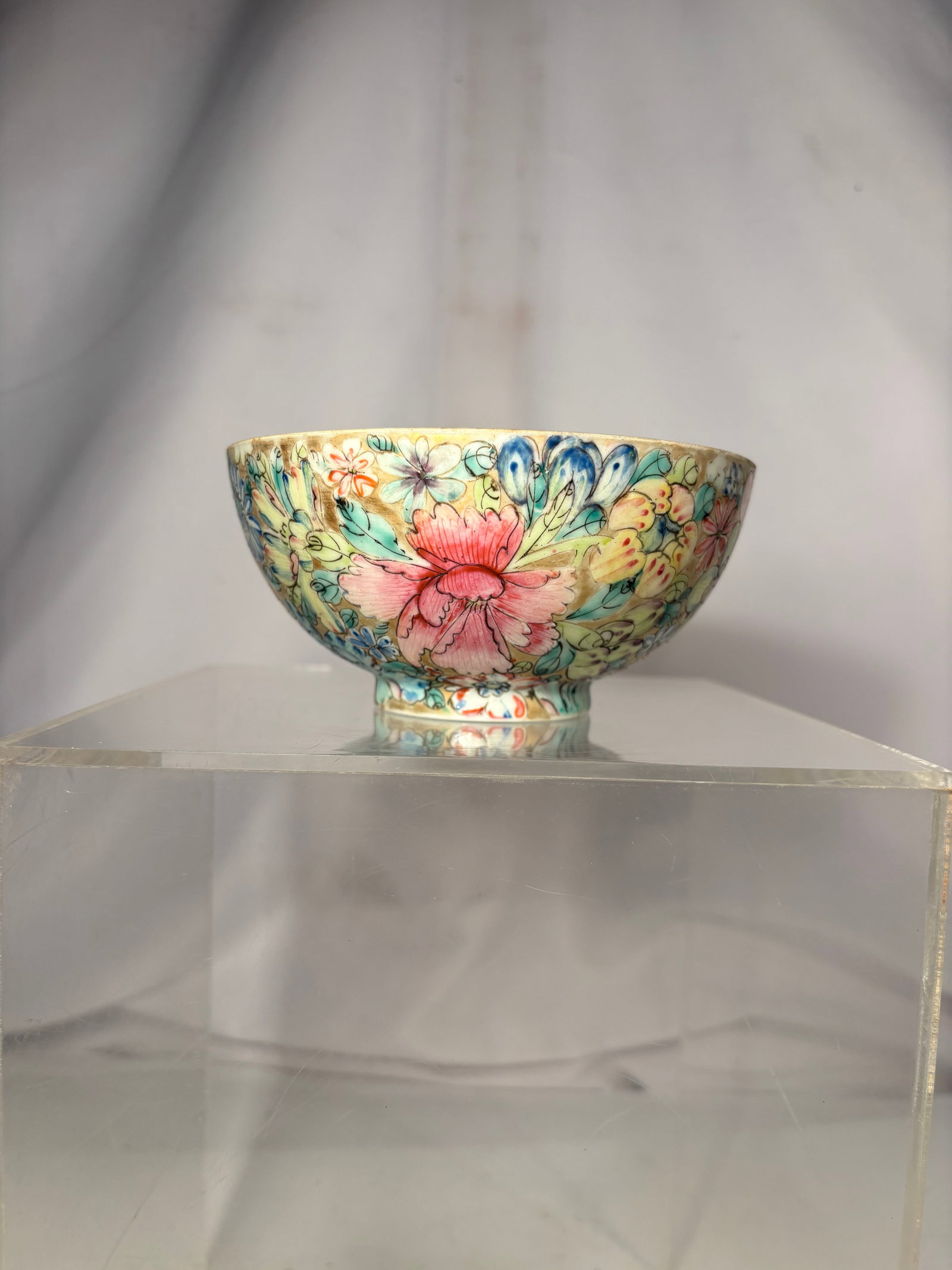Chinese Famille Rose Millefleurs Dragon Bowl, Qianlong Mark: A Chinese porcelain bowl densely decorated in famille rose enamels with the “Hundred Flowers” or millefleurs pattern. The interior is centered by an iron-red dragon medallion among stylized cl