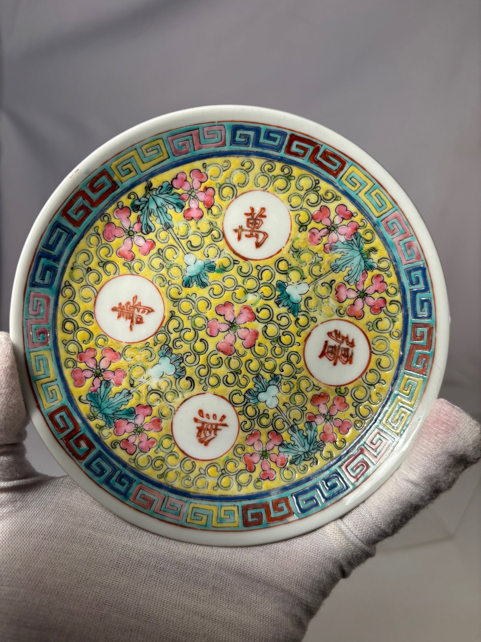 A Chinese Famille Rose Porcelain Plate with Floral Scrolls and Shou Medallions With Guang Xu Mark: Qing dynasty(1644-1912); A Chinese famille rose porcelain plate decorated with a dense yellow-ground floral scroll pattern, centered with four circular medallions each bearing auspicious characters. T