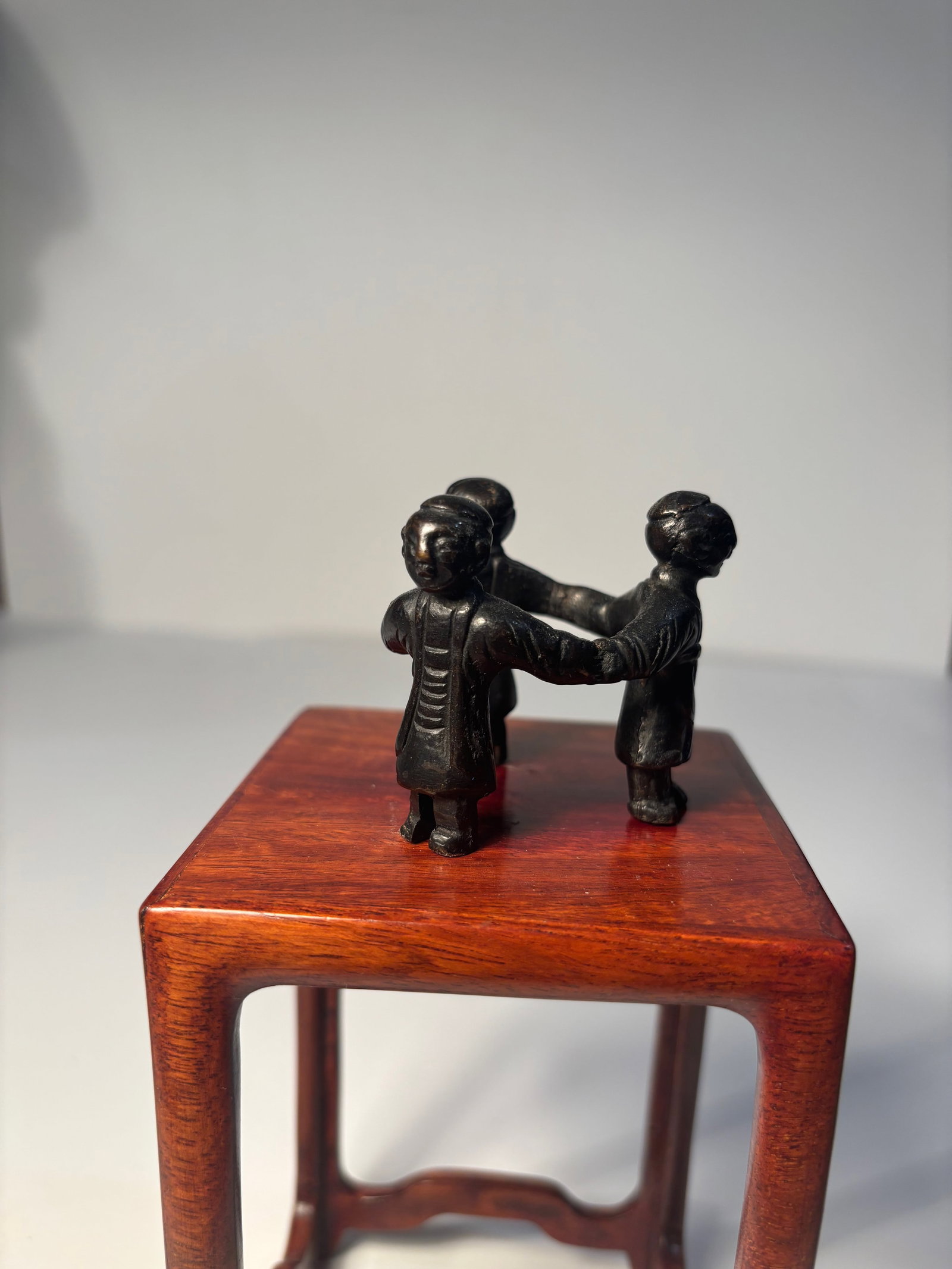 A Chinese three boys bronze statue: Ming Dynasty(1368-1644); This appears to be a small figurine sculpture of three interconnected figures in traditional clothing, made a dark-toned material such as bronze .Dimensions? Height: 2 inches.