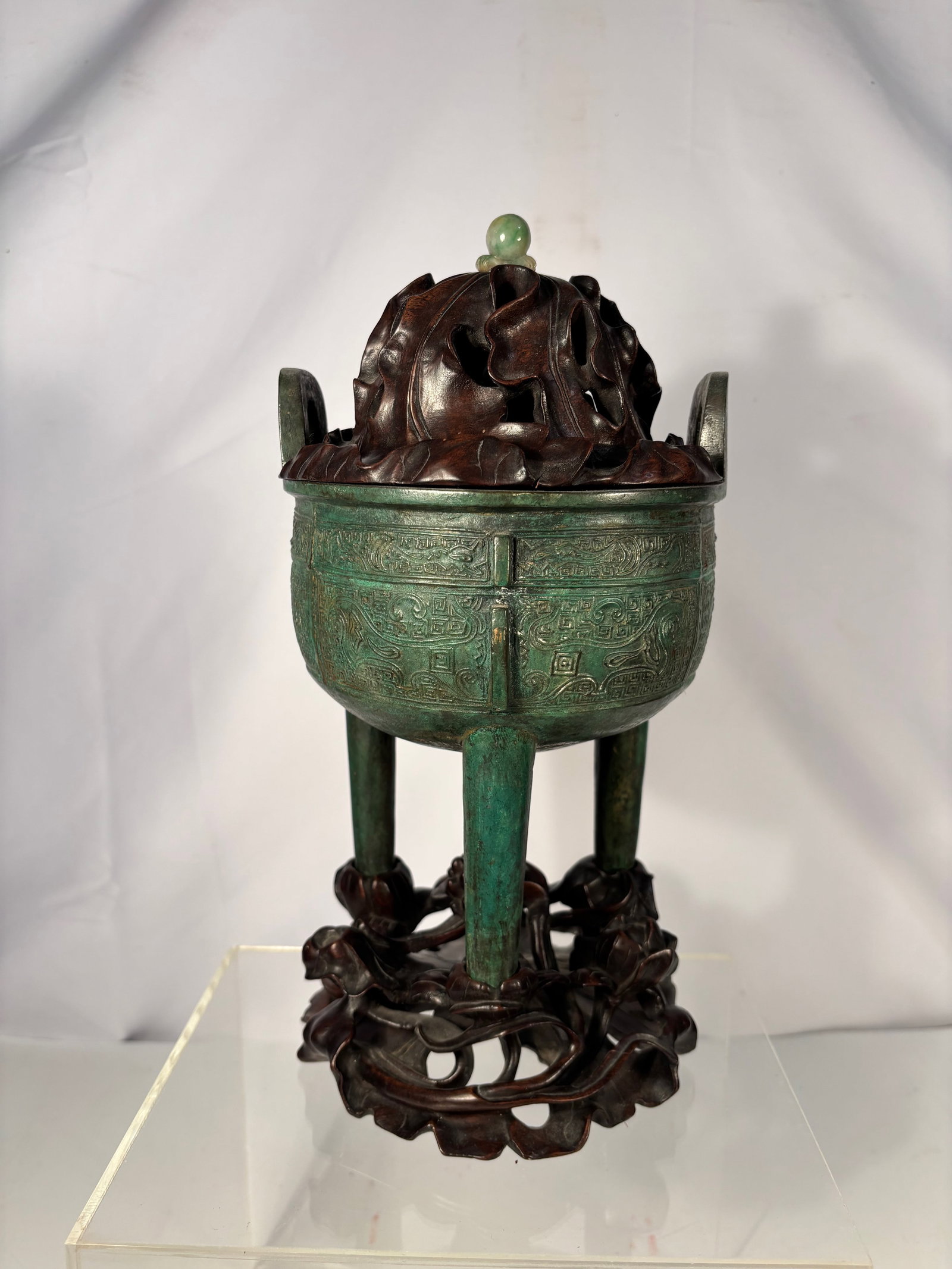 AN ARCHAISTIC BRONZE RITUAL TRIPOD VESSEL, DING: Qing Dynasty or early , Chinese bronze tripod censer, ding-form, featuring two upright loop handles and three tapered legs. The body is cast with decorative bands in a geometric archaistic motif. The 