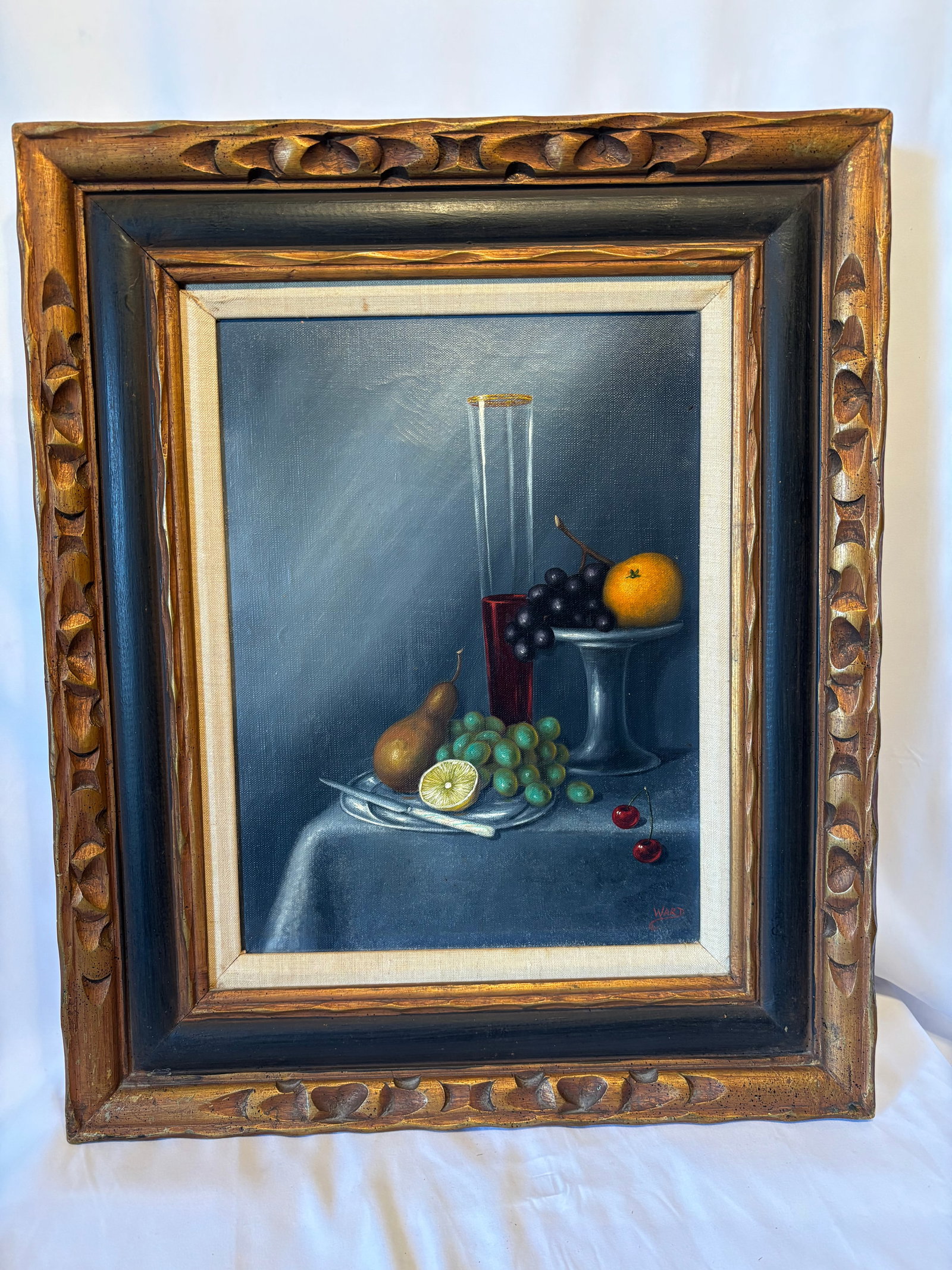 Ward Signed Still Life Oil Painting: Oil painting on canvas (or board) depicting a traditional still life arrangement with grapes, citrus, pear, cherries, and glassware upon a draped table. Executed in a realist style with dark