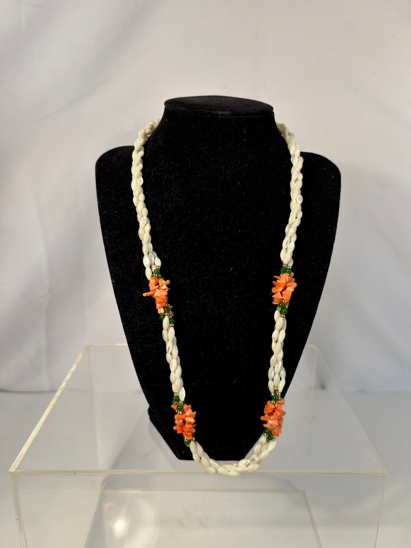 A mother-of-Pearl, Coral, and Green Jade Bead Necklace: A vintage triple-strand necklace featuring twisted white mother-of-pearl beads, punctuated by floral cluster accents of natural salmon coral chips, small green jade (or jadeite) beads, and gilt metal 