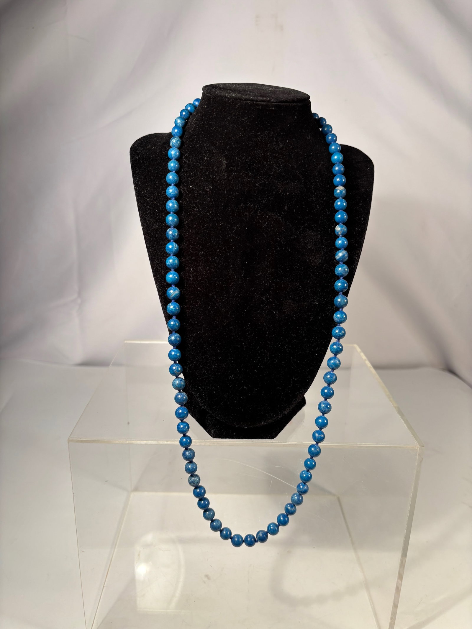 A Lapis Lazuli Bead Necklace: This necklace is composed of natural lapis lazuli round beads, displaying a deep blue color with natural mineral veining and tonal variation characteristic of lapis lazuli. The beads are individually 