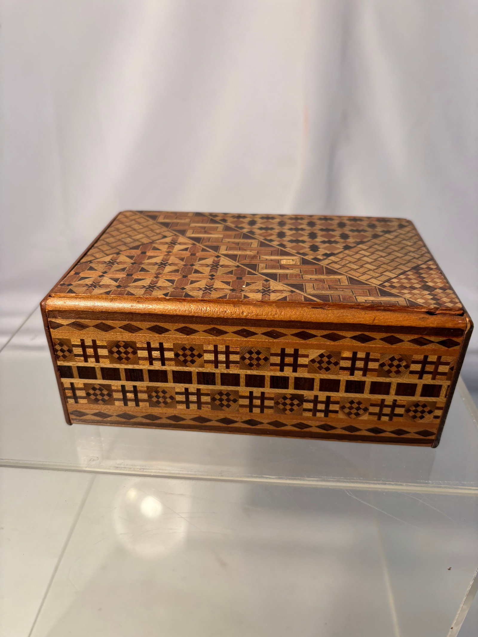 Japanese Yosegi Marquetry Wooden Puzzle Box: Japanese wooden box decorated throughout with intricate yosegi marquetry geometric inlay patterns in contrasting woods. Likely Hakone work. Having fitted lid and finely executed parquetry decoration. 