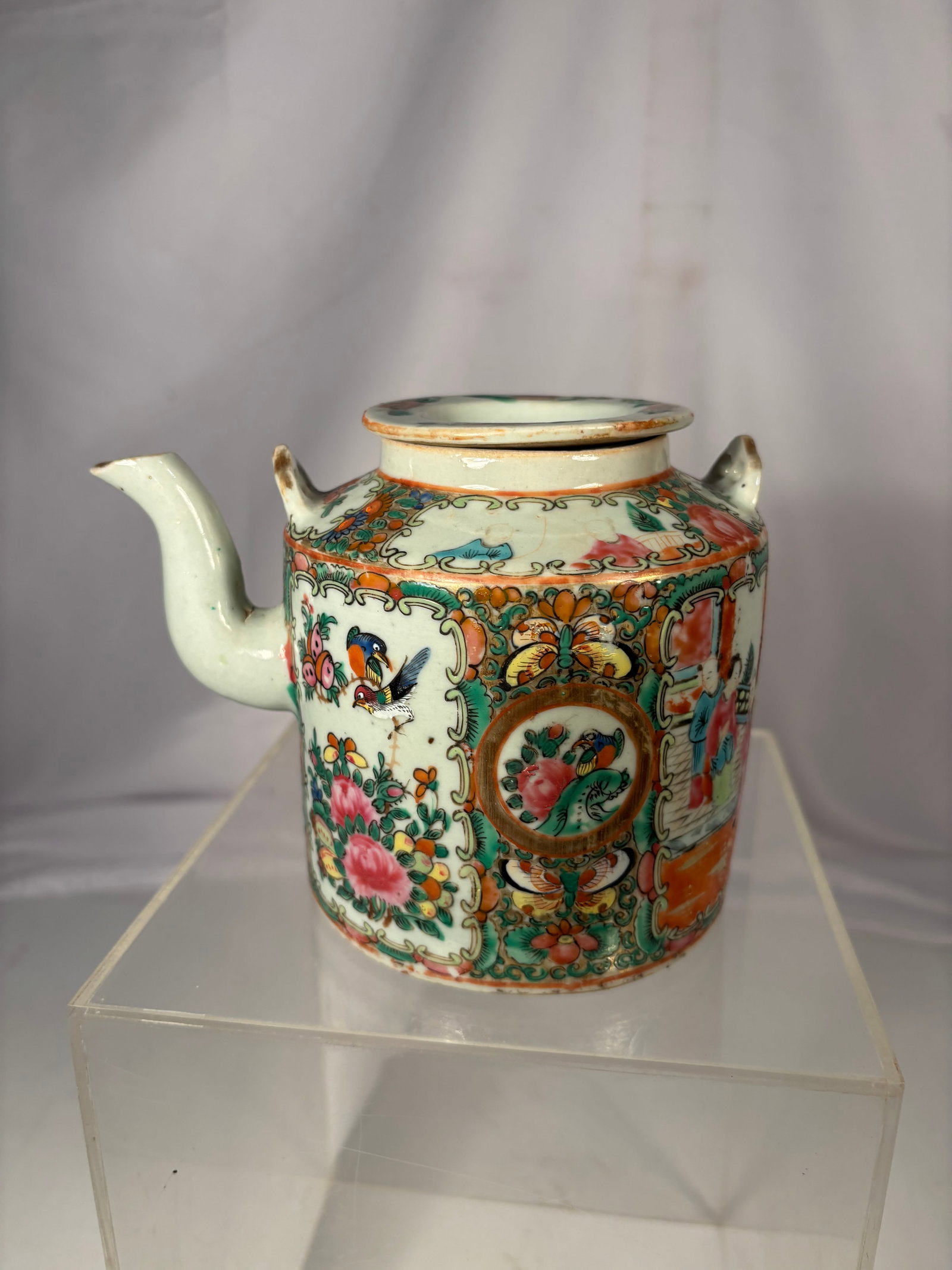 A Chinese Canton Famille Rose Porcelain Teapot Late Qing Dynasty, 19th Century: A Chinese Canton famille rose porcelain teapot decorated with alternating figural court scenes and floral panels enclosed by elaborate gilt and green scrollwork borders. The body is further embellishe