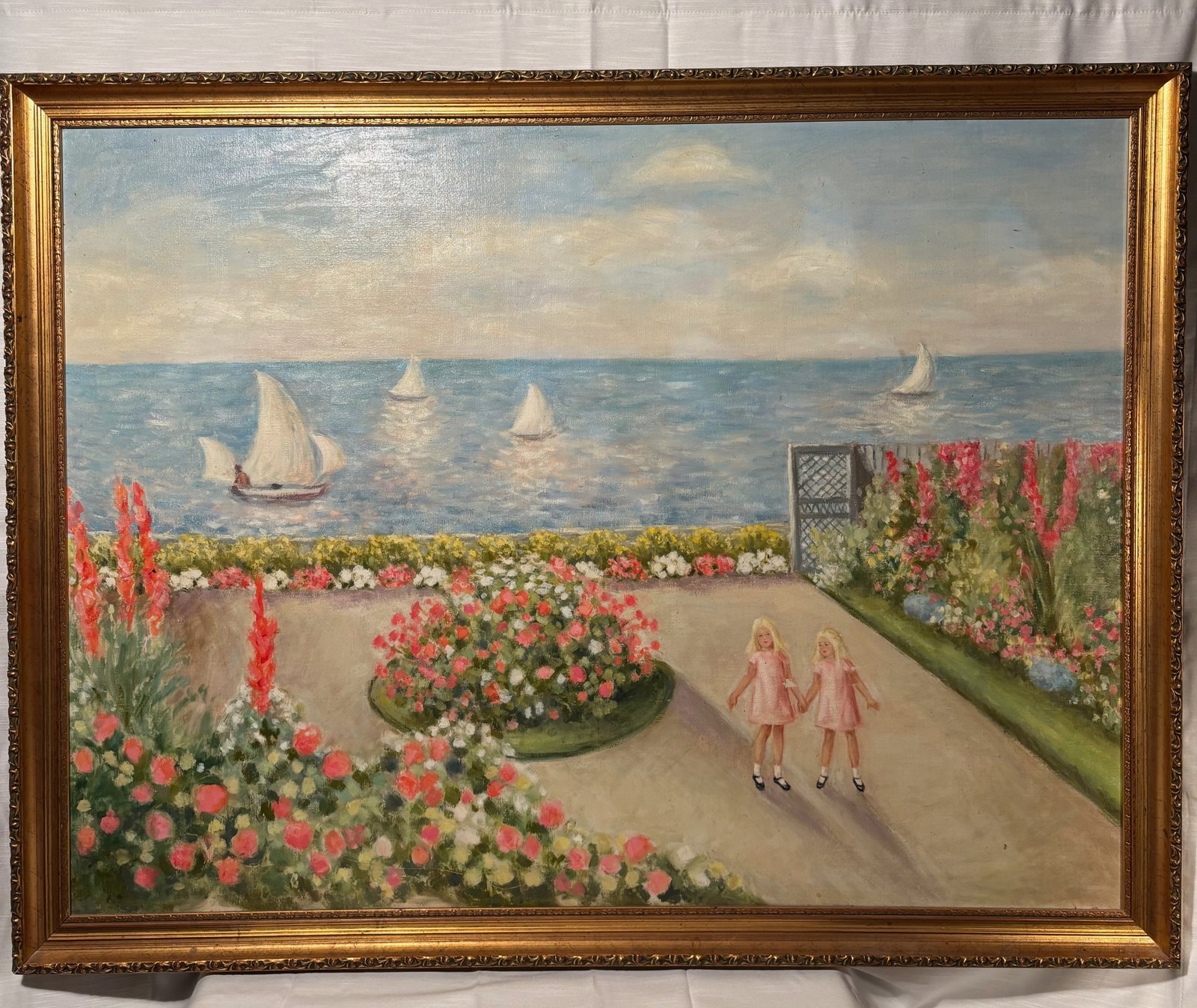 Large Coastal Garden Painting with Sailboats and Figures, 41 x 31.5 in: Large decorative coastal garden painting depicting a bright seaside terrace overlooking shimmering blue waters with sailboats in the distance.The foreground features abundant blooming floral beds and 