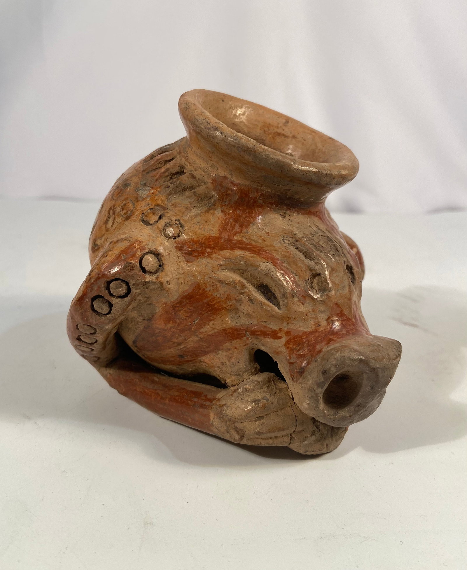 Pre-Columbian Colima Terracotta Animal Effigy Vessel: A Pre-Columbian terracotta effigy vessel from the Colima (or Nayarit) culture of West Mexico, modeled in the form of a stylized animal with a prominent snout, stamped circular decorations, and red sli