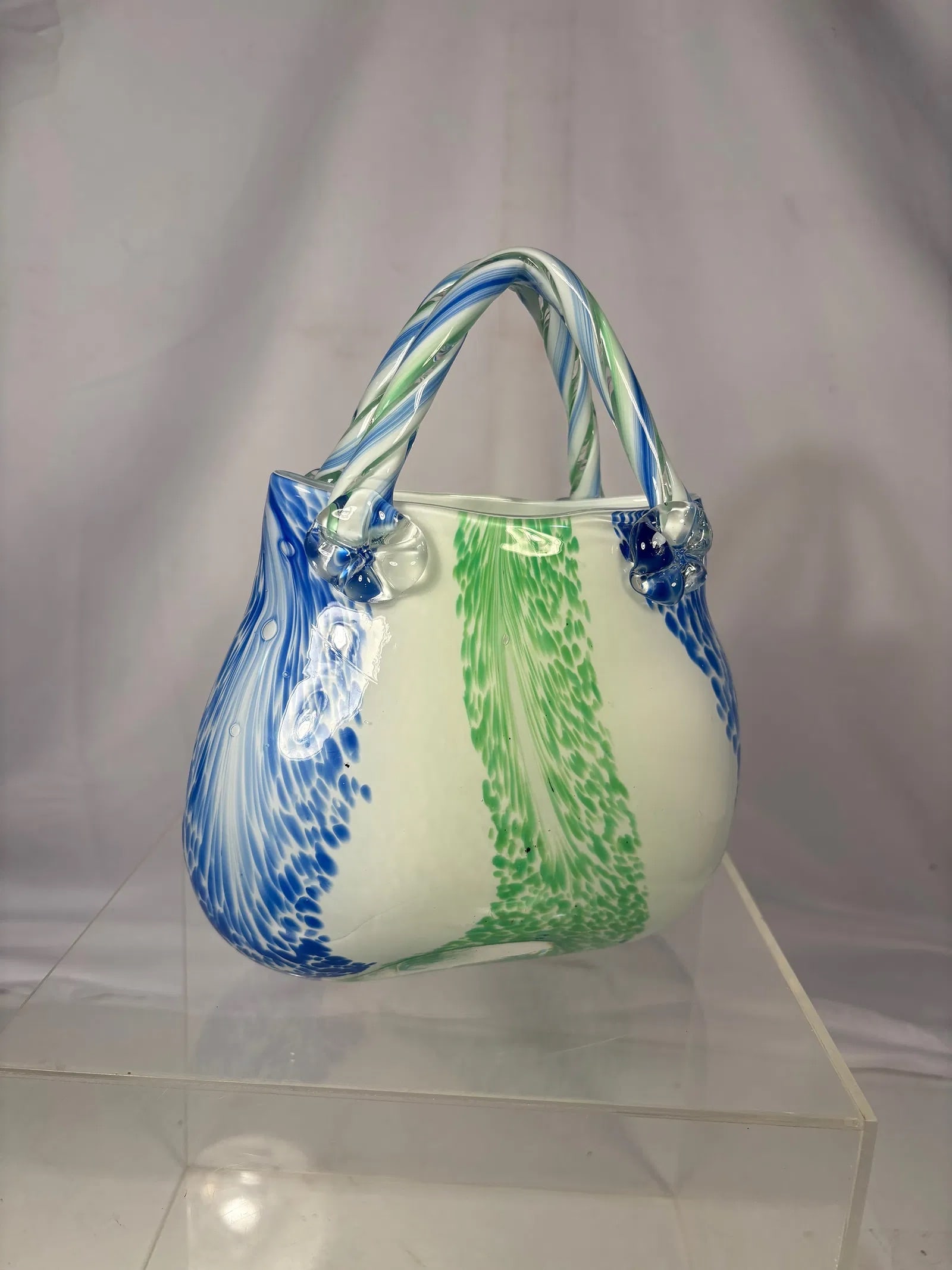 Murano Style Hand Blown Art Glass Basket: Murano-style hand blown art glass basket featuring a white ground with blue and green pulled-feather decoration. The free-form body is accented with a twisted glass handle and applied glass terminals.