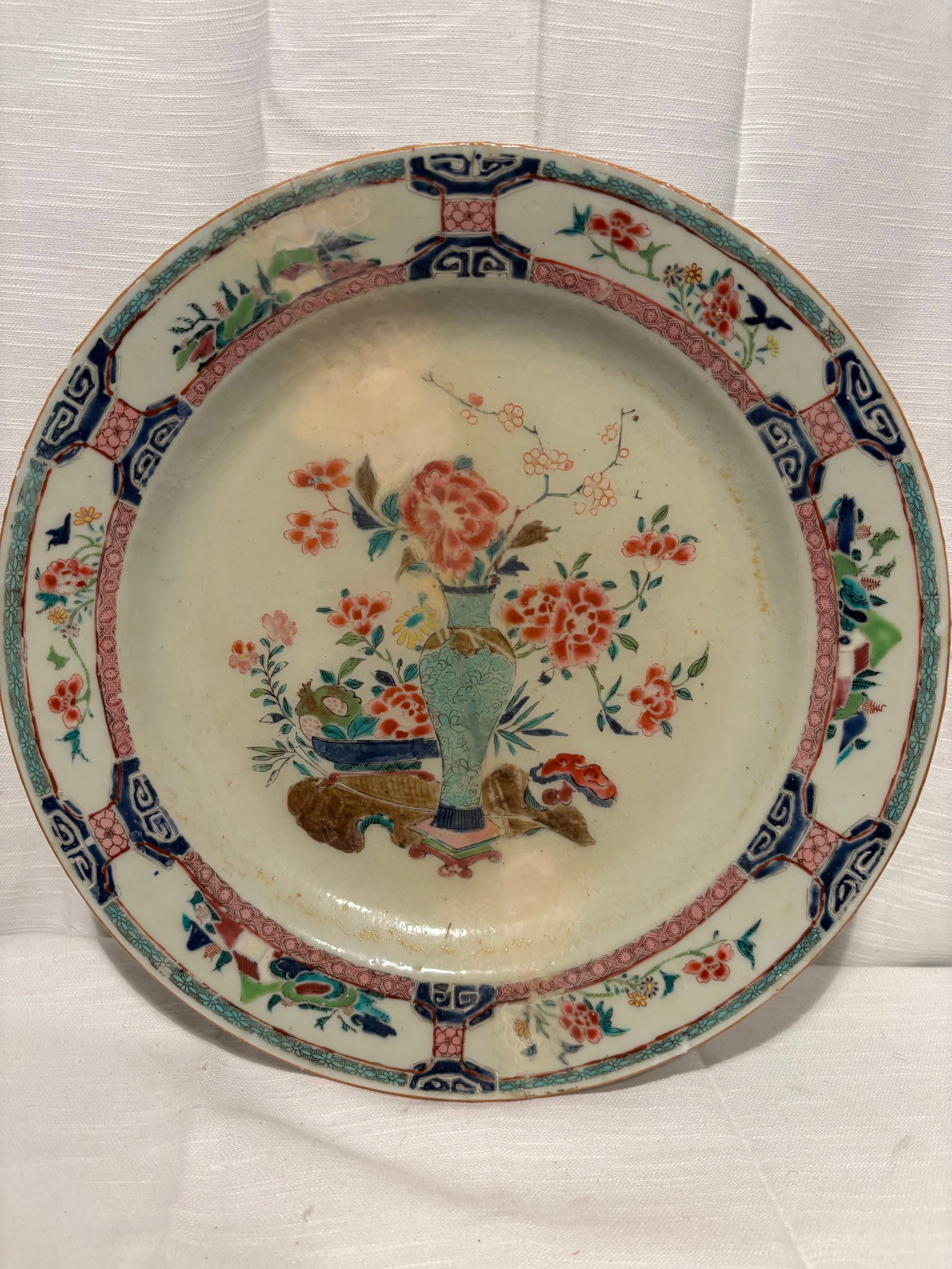 A Chinese Famille Rose Enamel Porcelain Plate with Floral Vase Decoration,: 18th century, A Chinese porcelain plate decorated in famille rose enamels, featuring a central vase of flowers motif rendered in soft polychrome tones. The cavetto is surrounded by a decorative border