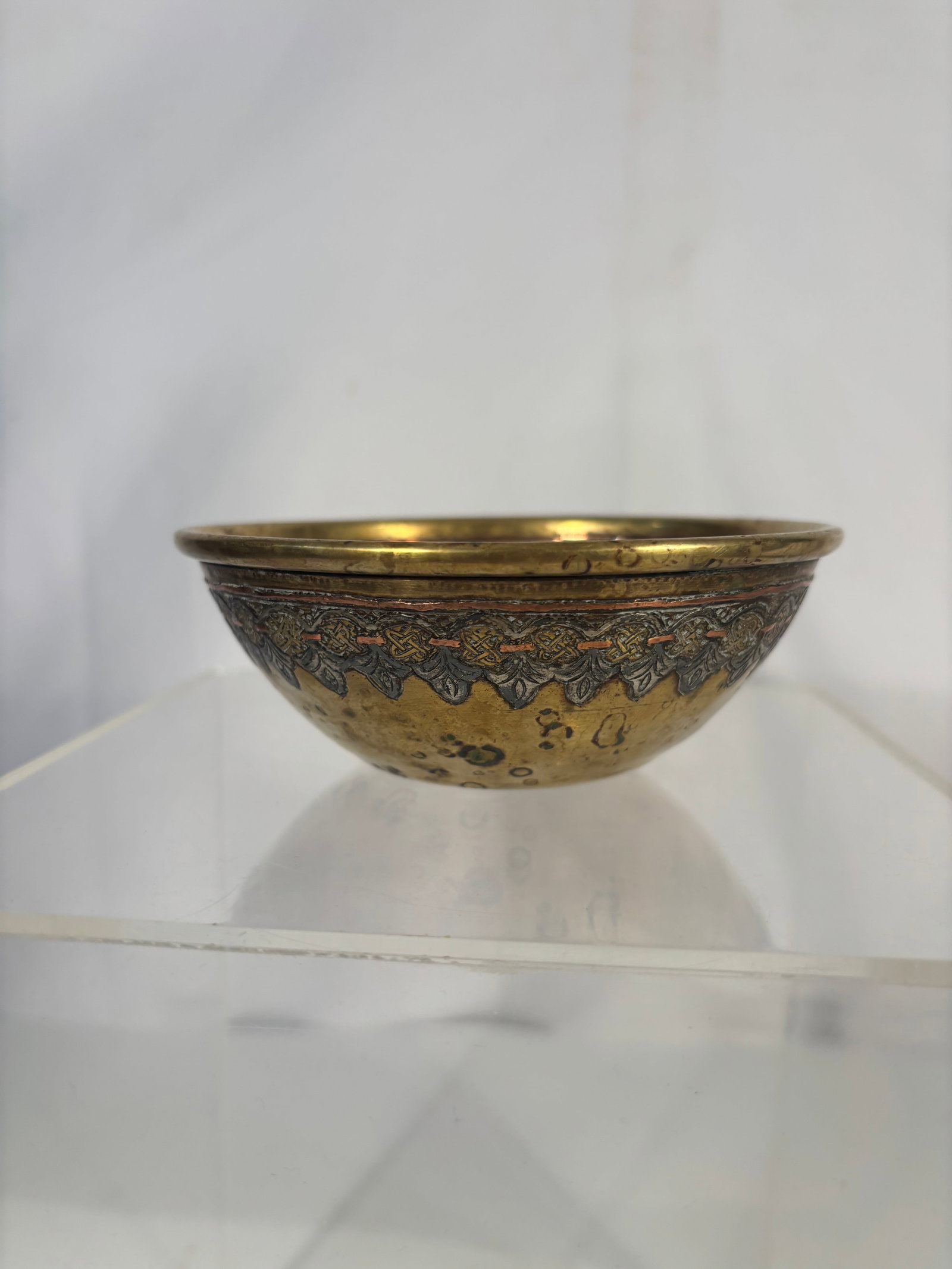 An Antique Middle Eastern Damascene Brass Healing Bowl with Silver & Copper Inlay: An antique Middle Eastern brass or gilt copper bowl, likely Damascus work from the late 19th to early 20th century, richly decorated with silver and copper inlay. The interior displays concentric band