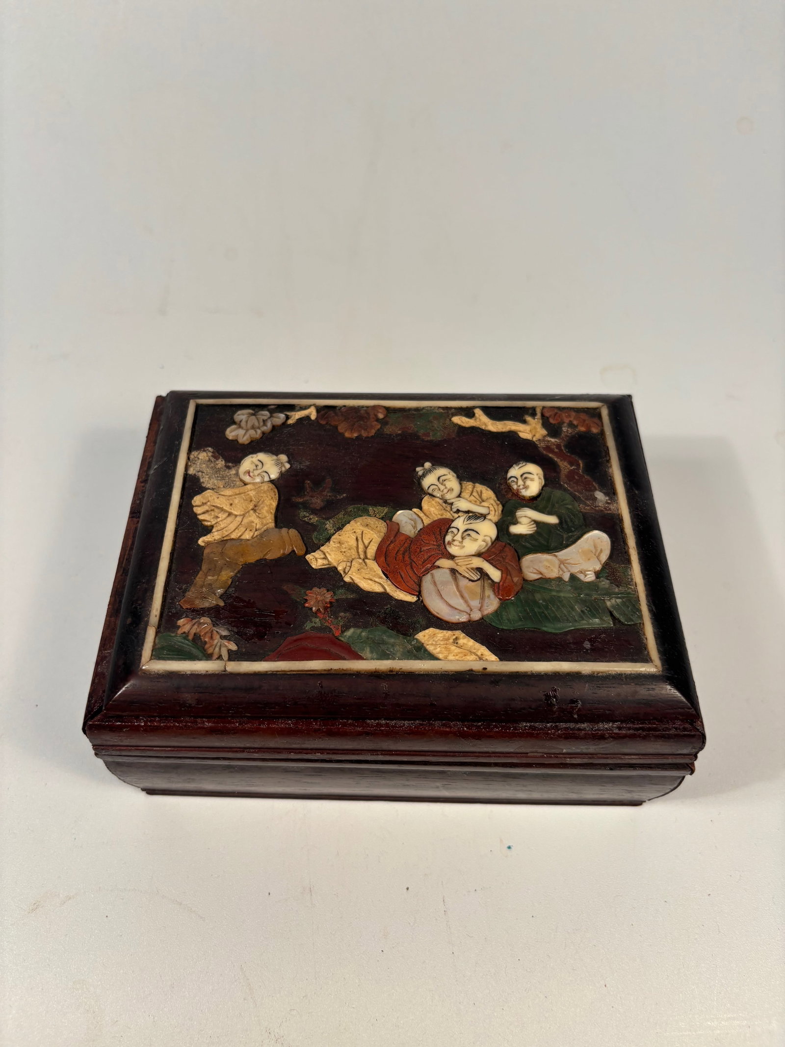 A Chinese HUANGHUALI /ROSEWOOD Box with Inlaid Figural Panel: Qing Dynasty (1644-1912); the lid featuring an intricate inlaid figural scene with scholars or immortals in a garden landscape. Materials include carved bone, colored stones, and lacquer. Dimensions?L