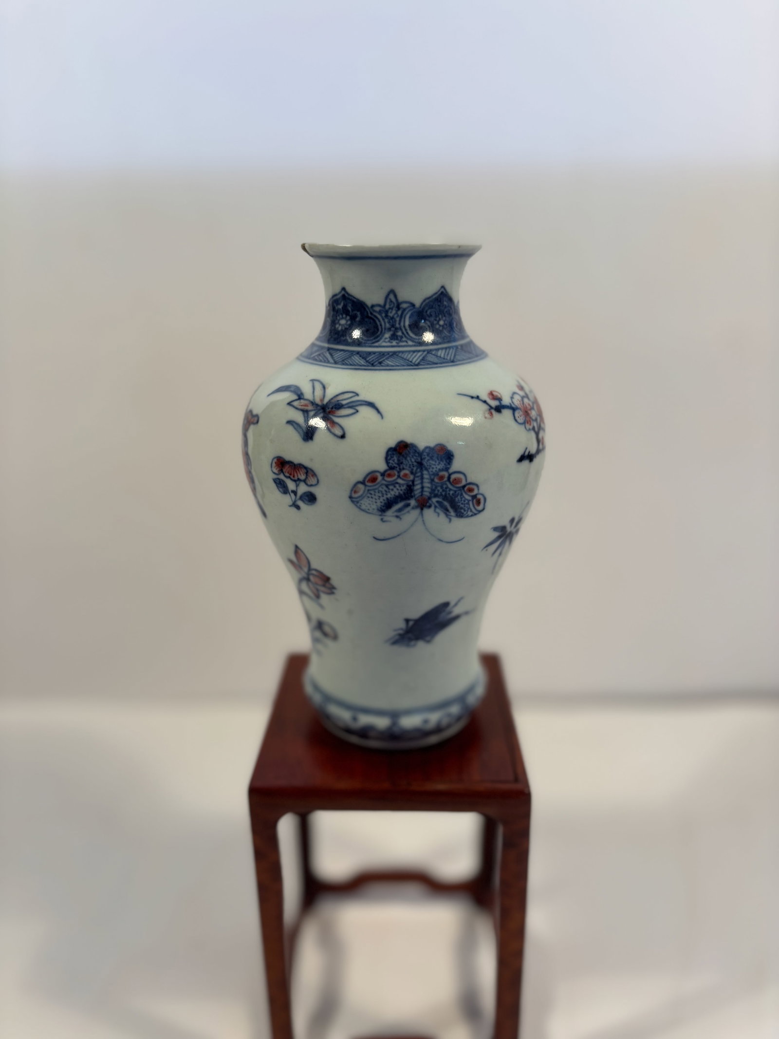A Chinese blue and iron red porcelain Meiping vase: 19th century to 20th century; A Chinese porcelain vase of baluster form, decorated with underglaze blue and iron-red enamel butterflies among floral sprays. The design combines traditional cobalt blue