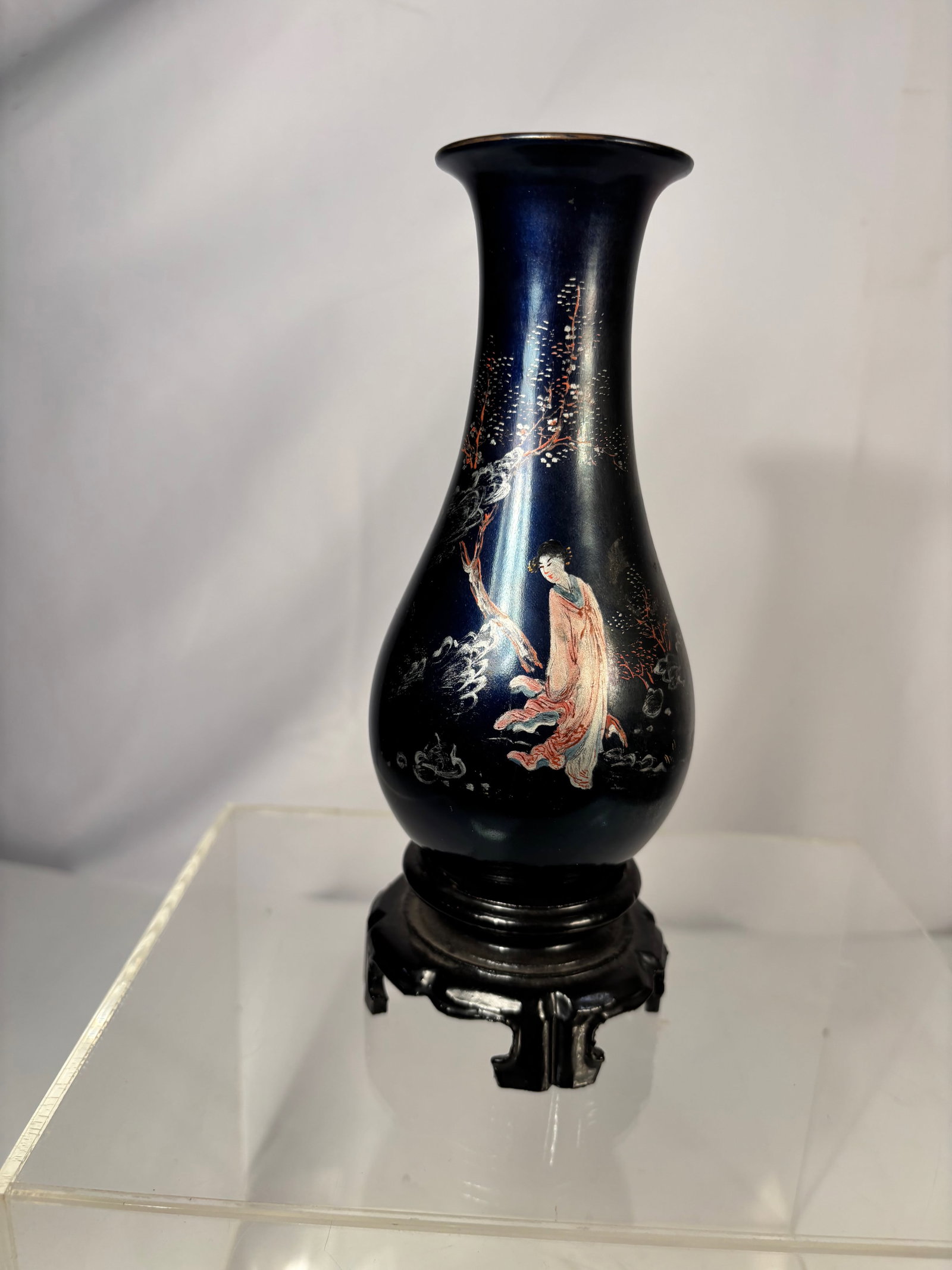 A Chinese Black Lacquer Style Vase with Figure Decoration: Black lacquer style decorative vase featuring hand-painted figure and landscape motifs. Mounted on a fitted wooden stand. Base marked “Lian Gin Brand, Made in China.”Height: 8 inches.