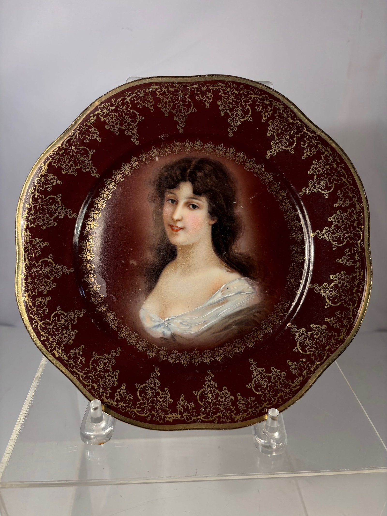 A Royal Vienna Hand-Painted Portrait Plate, Bavaria: Early 20th century German porcelain portrait plate bearing “Royal Vienna” and “Mignon Z.S.& Co Bavaria” marks. Featuring a hand-painted female portrait set against a deep burgundy grou