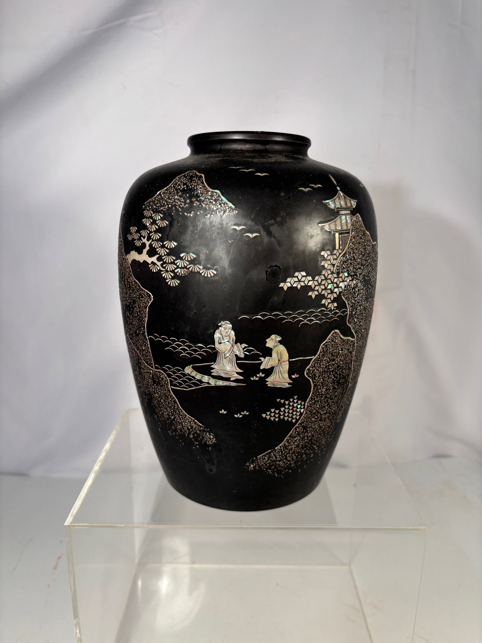 An Asian Black Lacquered Metal Vase with Mother-of-Pearl Landscape Inlay: Asian black lacquered metal vase featuring finely inlaid mother-of-pearl decoration. The body depicts a continuous landscape scene with scholars in conversation beneath pine trees, architectural pavil