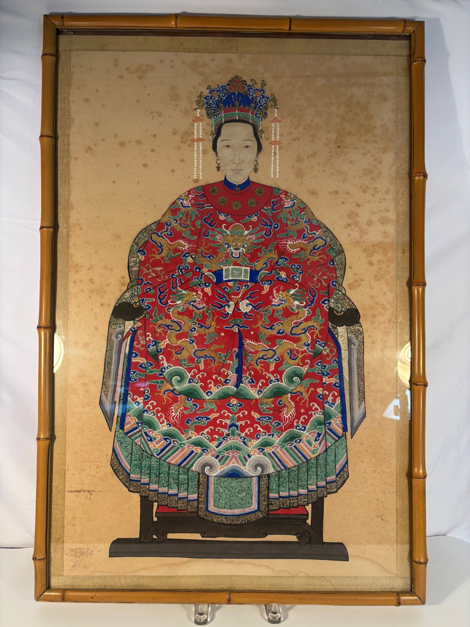 A Chinese Ancestor Portrait of a Noblewoman in Court Robes,: Qing Dynasty(1644-1912); A Chinese ancestor portrait, Qing Dynasty, 19th century. Painted in mineral pigments and ink on paper, depicting a seated noblewoman in a red dragon robe with elaborate phoeni