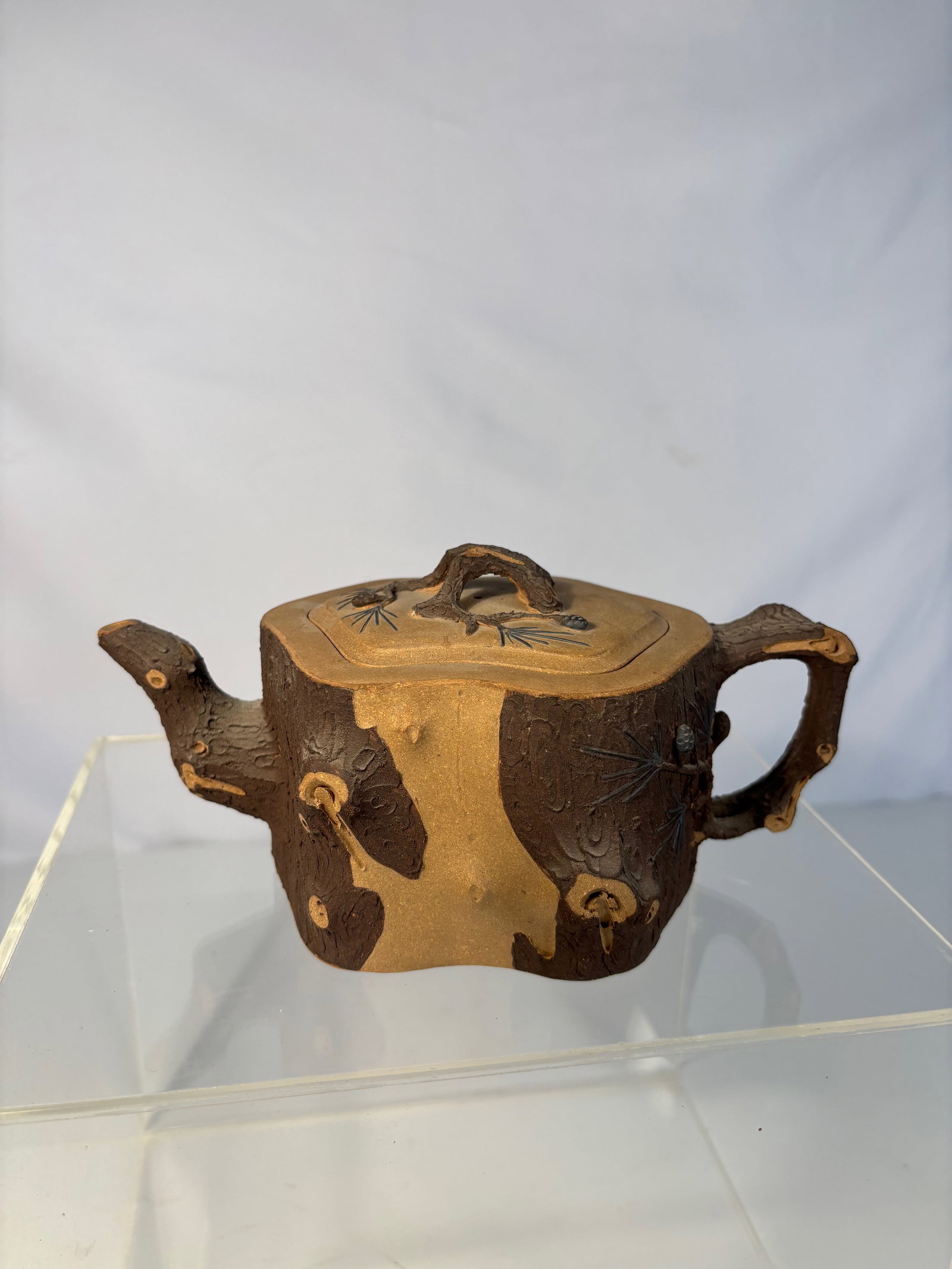 A Chinese Yixing Zisha Teapot with seal mark: Chinese Yixing zisha (purple clay) teapot, molded in the form of gnarled tree bark with relief pine needles and cones, the spout, handle, and knop formed as naturalistic branches. The underside with a