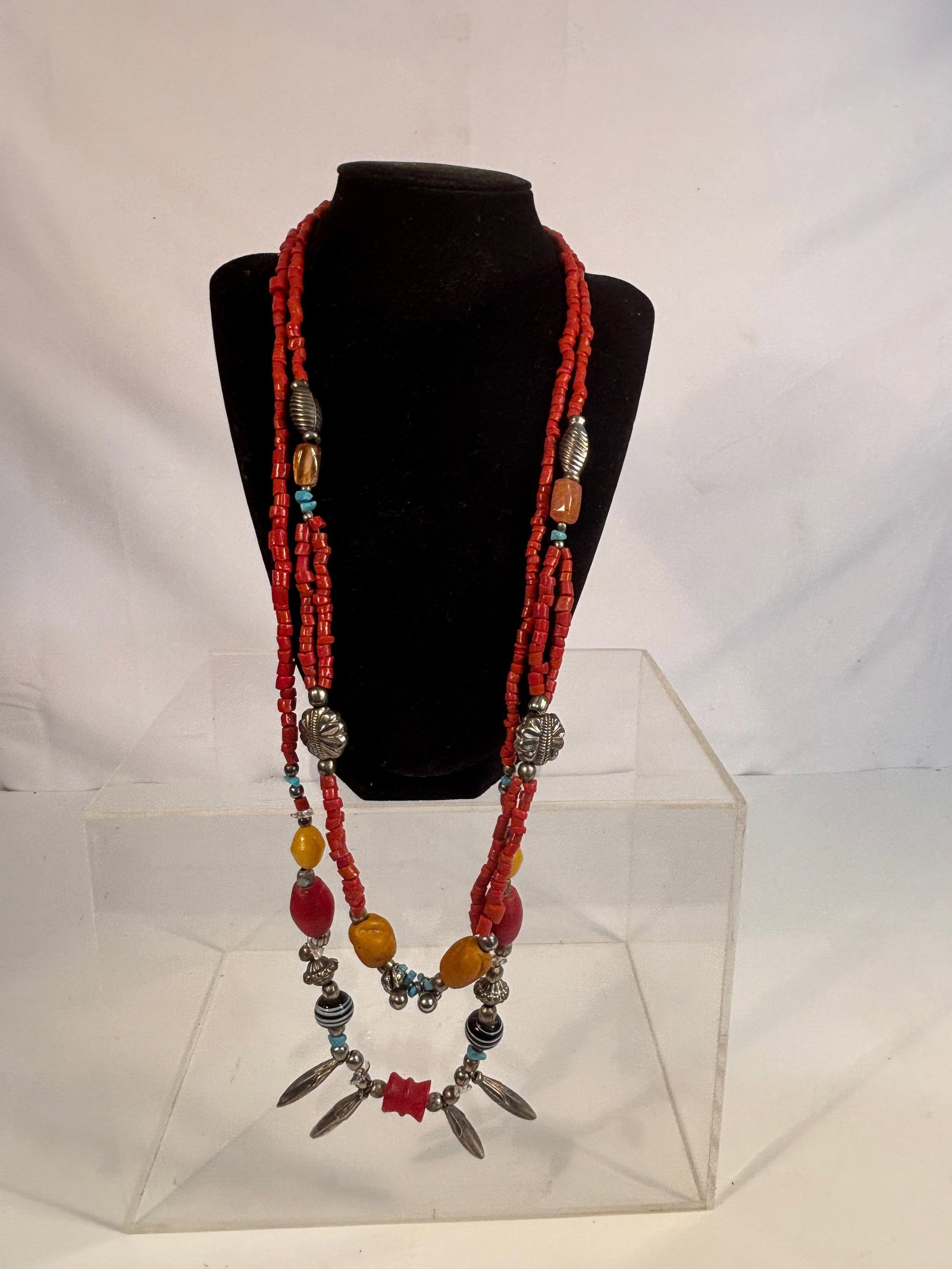 A Ethnic Multi-Strand Coral with turqoise and Bead Necklace: An ethnic multi-strand necklace composed of red coral beads, interspersed with larger amber-colored resin beads, silver elements, turquoise beads, and black-and-white striped glass beads. Likely Tibet