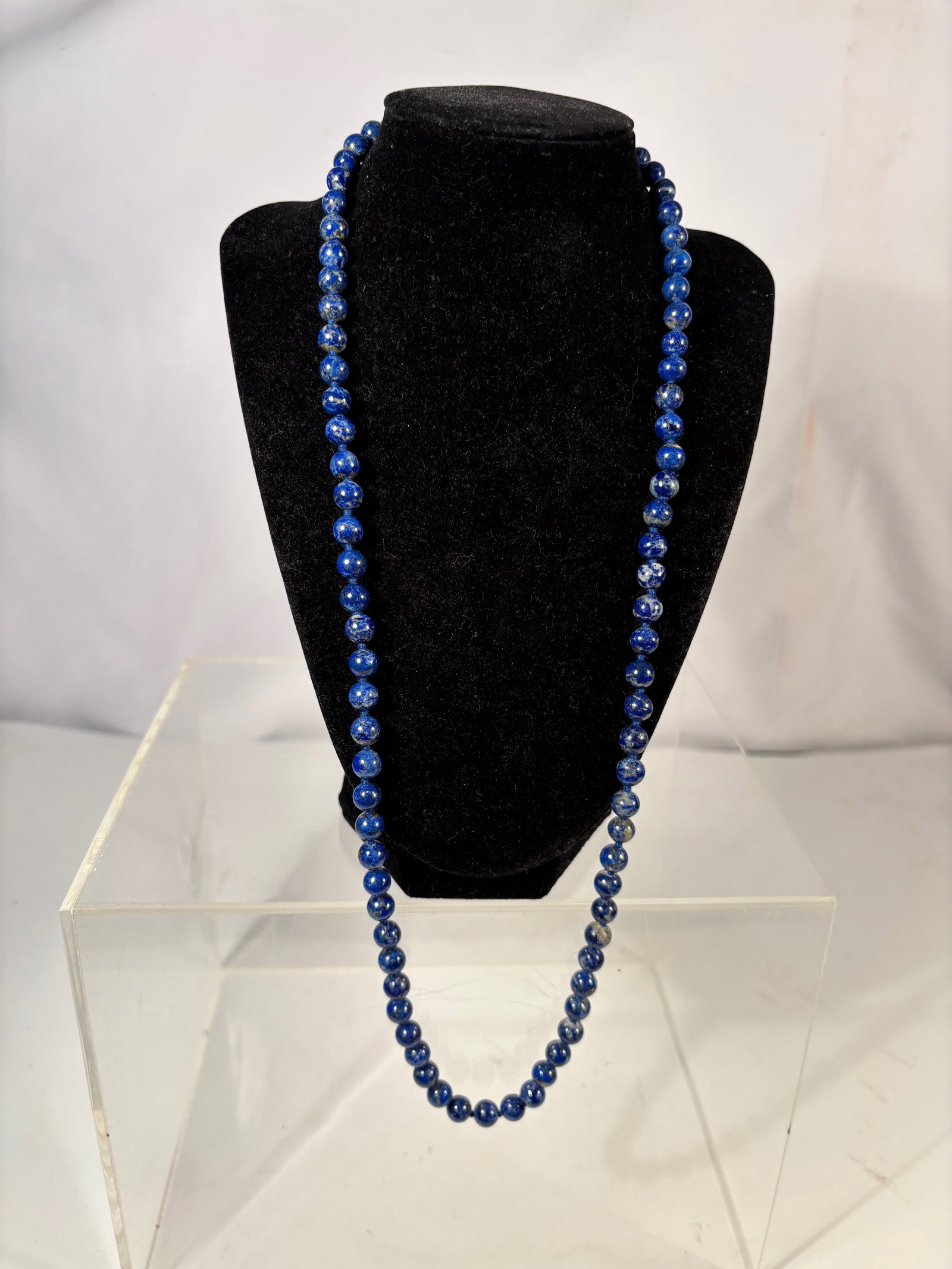 A Lapis Lazuli Bead Necklace: Necklace composed of small round lapis lazuli beads displaying deep cobalt blue coloration with natural mineral inclusions. Length: 29 inches.