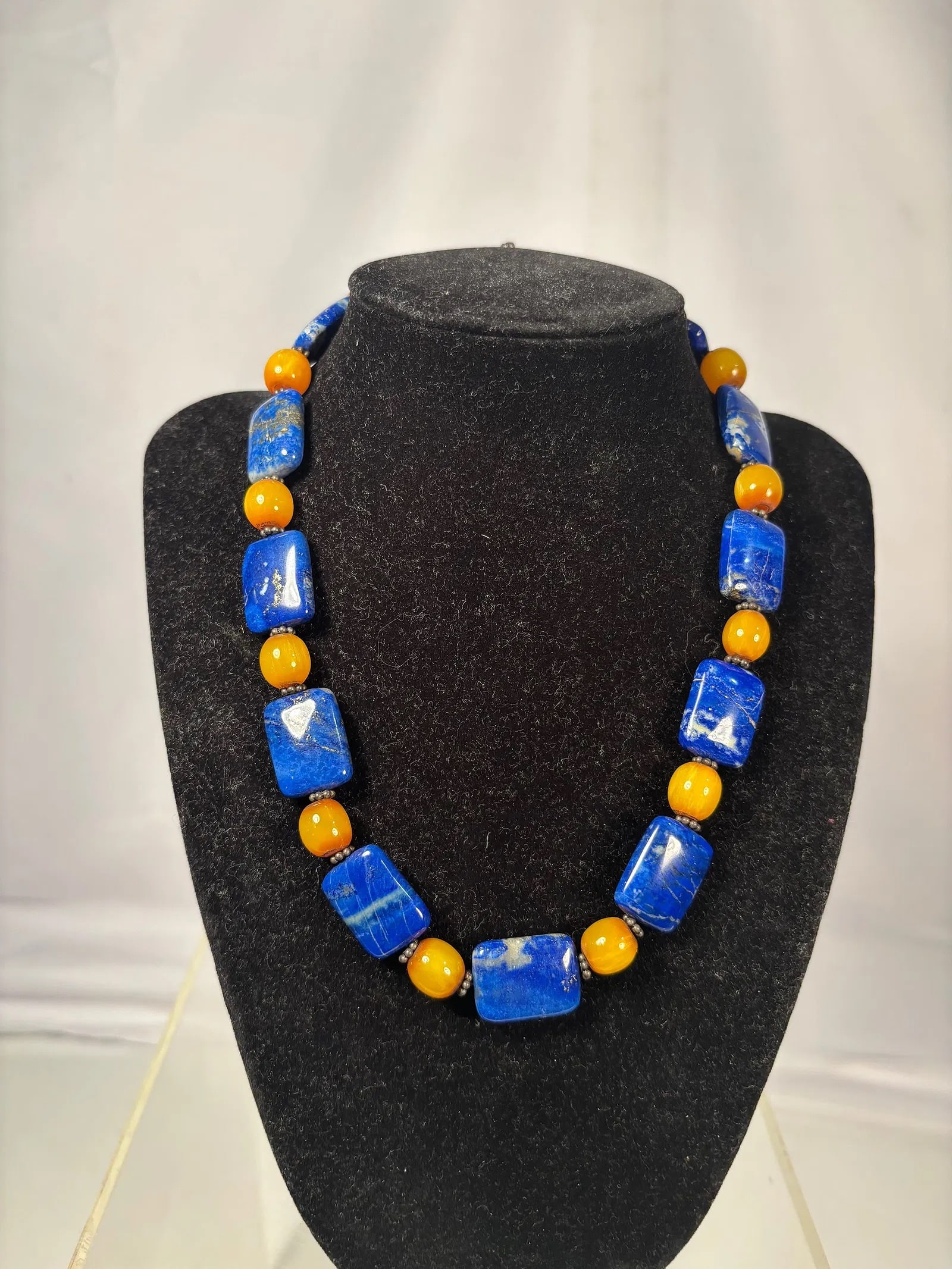 Southwestern Style Lapis Lazuli and Amber-Tone Bead Necklace: Handcrafted necklace featuring vivid cobalt-blue rectangular stone beads alternating with amber-tone round beads. Finished with decorative metal findings and a toggle clasp. The striking color contras