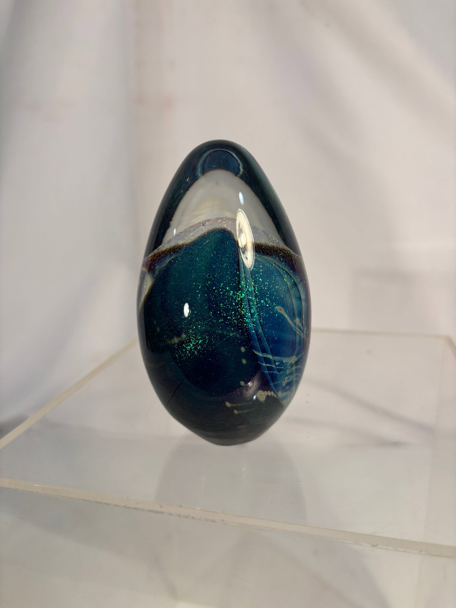Robert Eickholt Signed 1995 Blue Dichroic Art Glass Egg-Form Paperweight: A signed Robert Eickholt studio art glass paperweight of egg form, featuring deep cobalt-blue and teal glass with shimmering green dichroic inclusions, sweeping internal ribbons, and abstract white ac