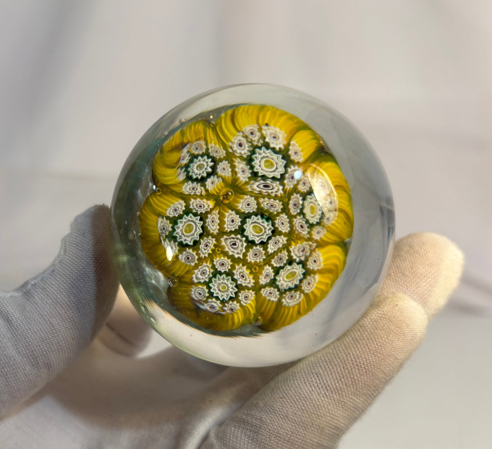 Vintage Murano-Style Yellow and White Millefiori Mushroom Art Glass Paperweight: A vintage Murano-style art glass paperweight featuring a domed clear glass body enclosing a mushroom-form arrangement of yellow and white millefiori floral canes. The design is accented with green det
