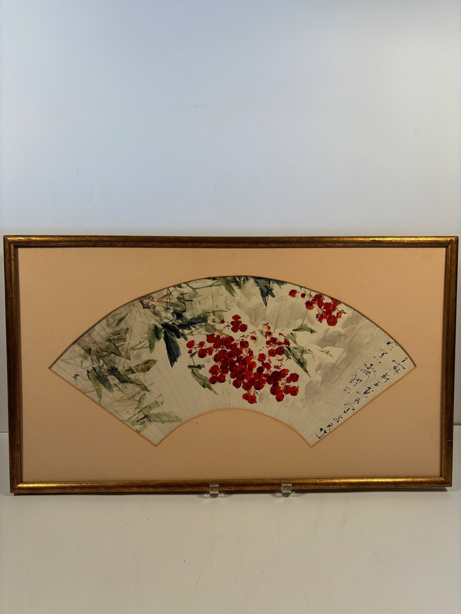 A Chinese ink and watercolor fan painting signed and dated: Qing Dynasty (1644-1912); Red berries (likely nandina or similar winter berries) with bamboo and leafy plants — a classic seasonal motif in Chinese painting symbolizing resilience. There is a dedica