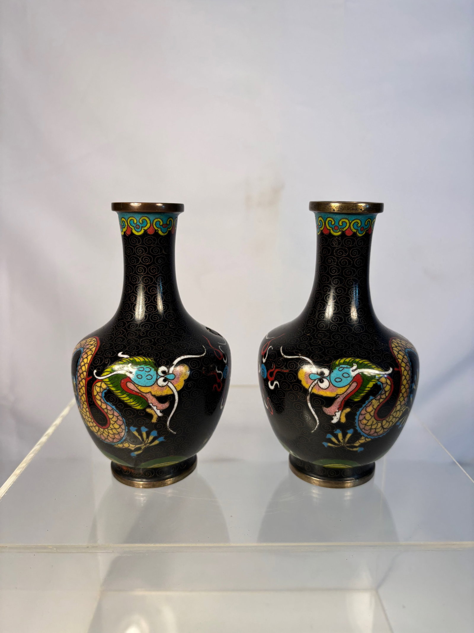 A pair of Chinese Cloisonné Enamel Vases with dragon Motifs: Qing Dynasty(1644-1912);Of globular form rising to a short cylindrical neck, decorated in cloisonné enamel with ruyi-style cloud scrolls in bright green against a dark ground, the design picked out i