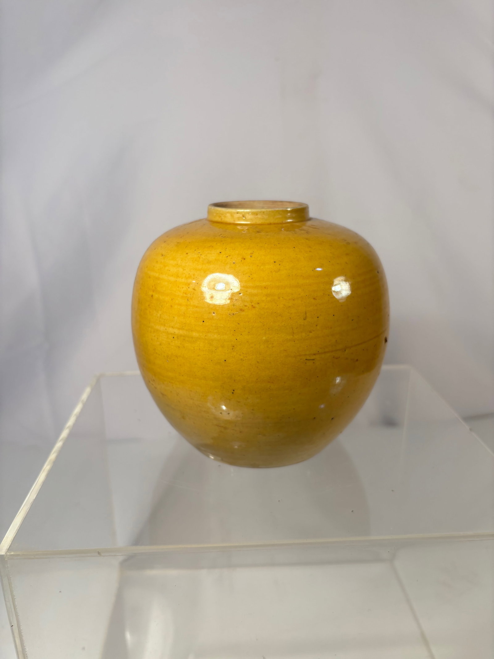 A Chinese Yellow-Glazed Porcelain Jar: Qing dynasty(1644-1912); The jar of compressed globular form with short neck and unglazed foot, evenly covered in a rich mustard-yellow glaze that stops neatly at the footrim, the interior glazed in a