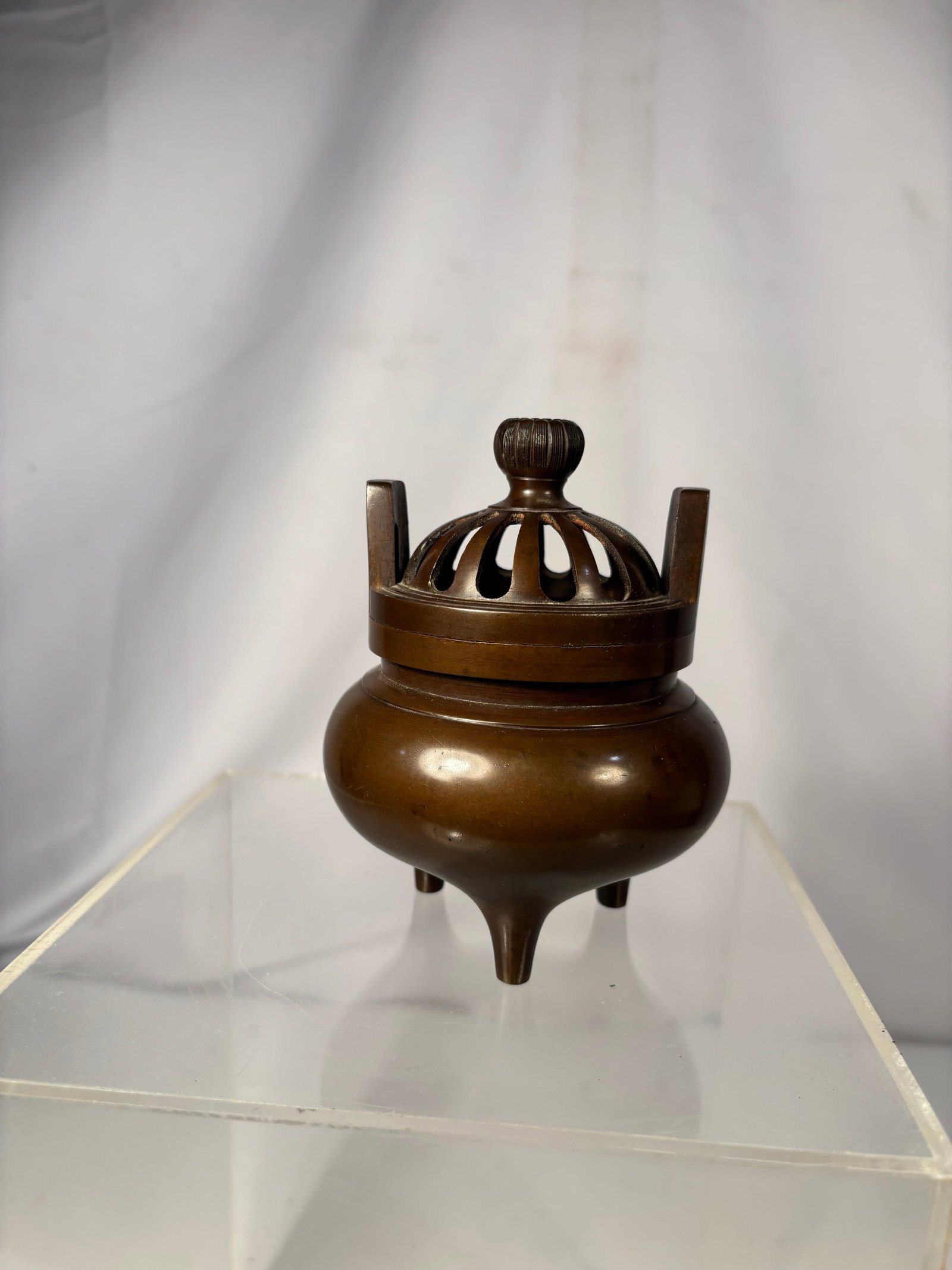 Japanese Patinated Bronze Tripod Incense Burner (Koro), Signed Made by Iga / Iya.: Japanese patinated bronze tripod incense burner, or koro, with a removable openwork domed cover and three upright handles. The base is engraved with the maker’s mark . The elegant form and warm brow
