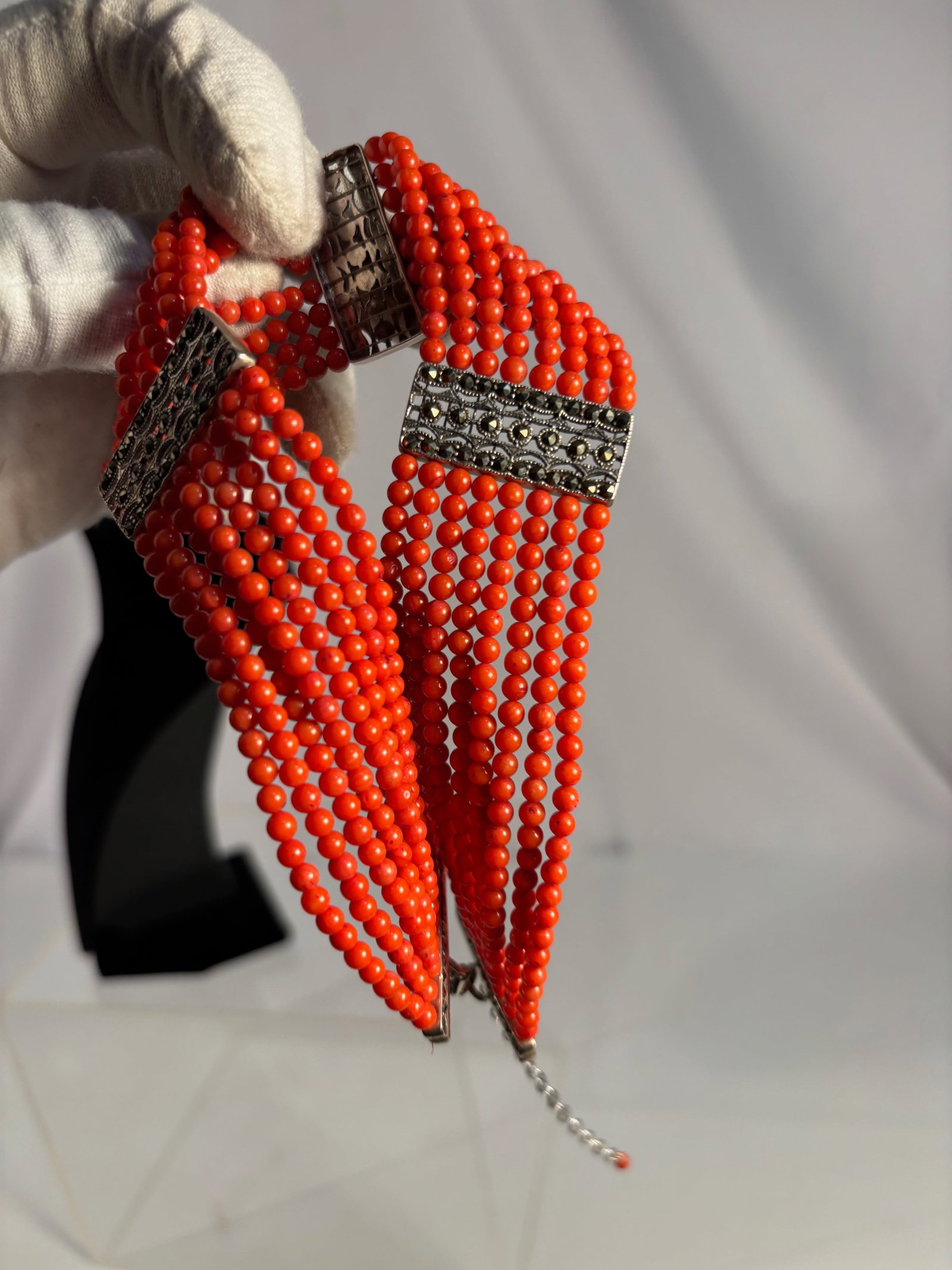 Multi-Strand Mediterranean Coral Choker Necklace with Silvered Separators, 12.5 in. + 3.5 in.: A dramatic choker necklace comprising twelve strands of polished red Mediterranean coral beads, interspaced with ornate silvered separators in scrolling relief. The bold design recalls traditional Eas