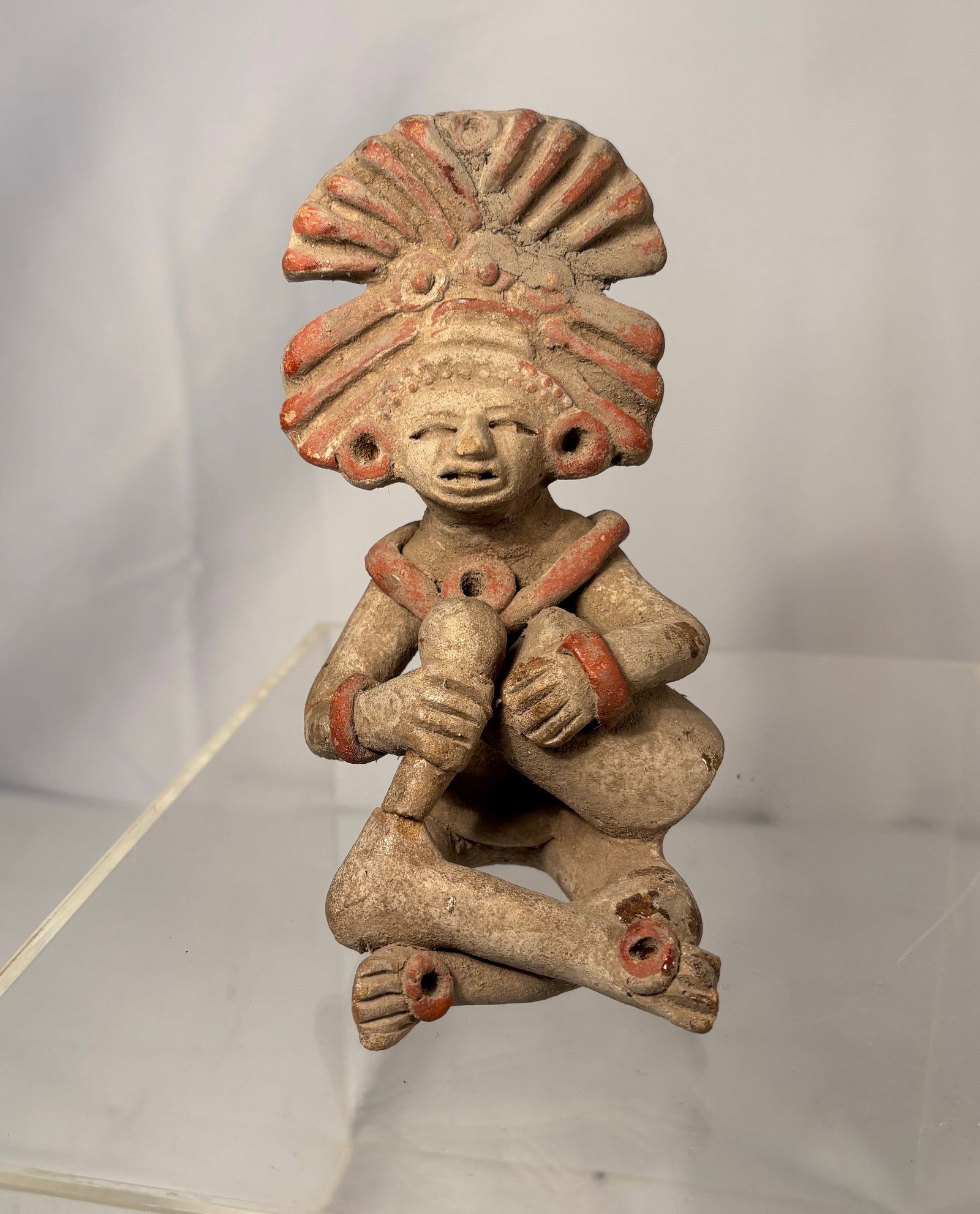 Pre-Columbian Terracotta Figure, with Headdress Reminiscent of Veracruz and West Mexican Forms: Terracotta figure in the style of Pre-Columbian West Mexican art, featuring a seated figure with an elaborate headdress and painted red highlights. While some visual elements loosely recall imagery se
