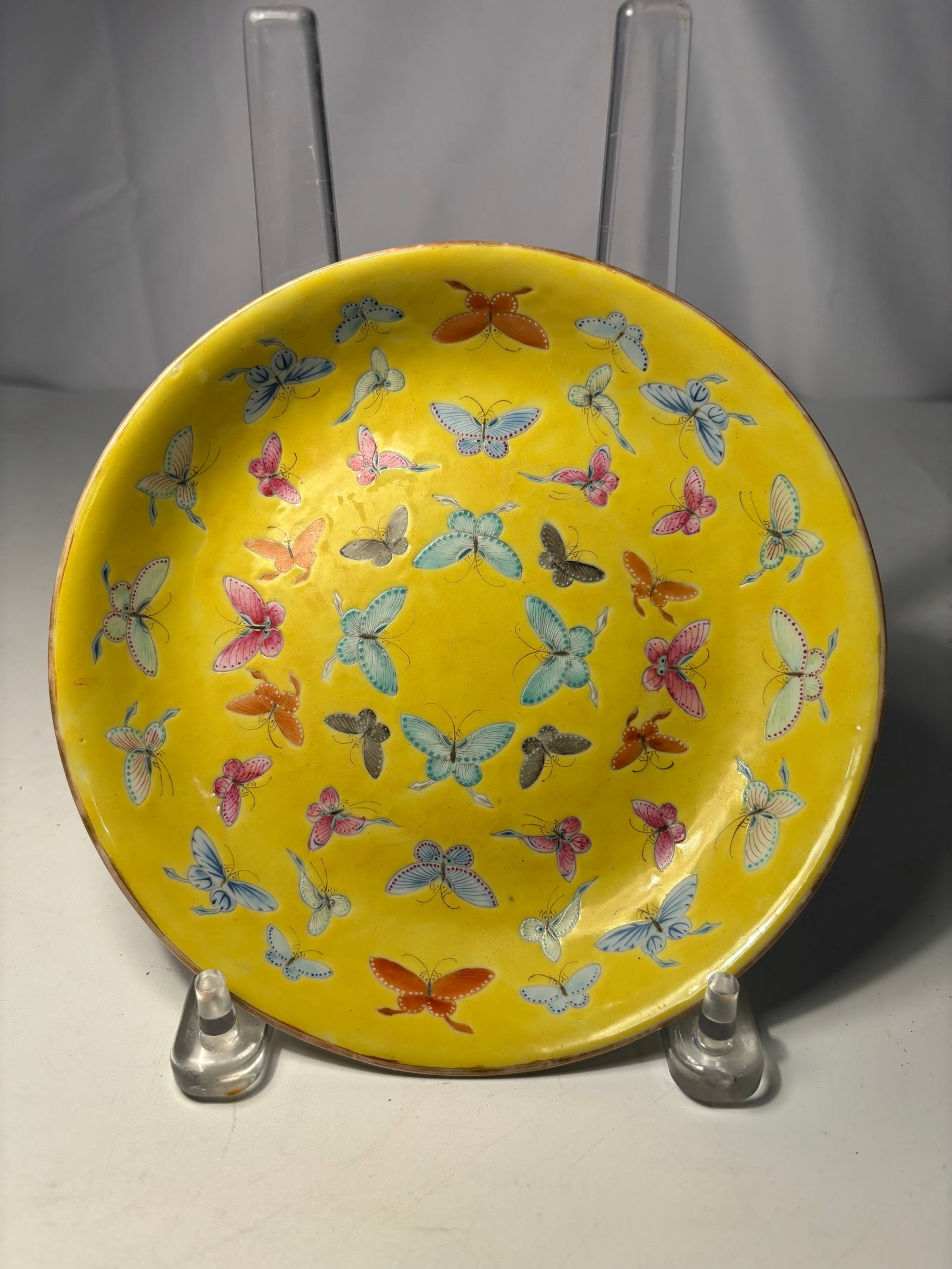 A Chinese Yellow Ground Famille Rose Butterfly Plate marked "Daqing Guangxu Nianzhi Six Characters: Qing Dynasty(1644-1912) ; A Chinese porcelain plate featuring a vibrant yellow ground decorated with numerous finely painted butterflies in famille rose enamels. The underside bears a six-character Gu