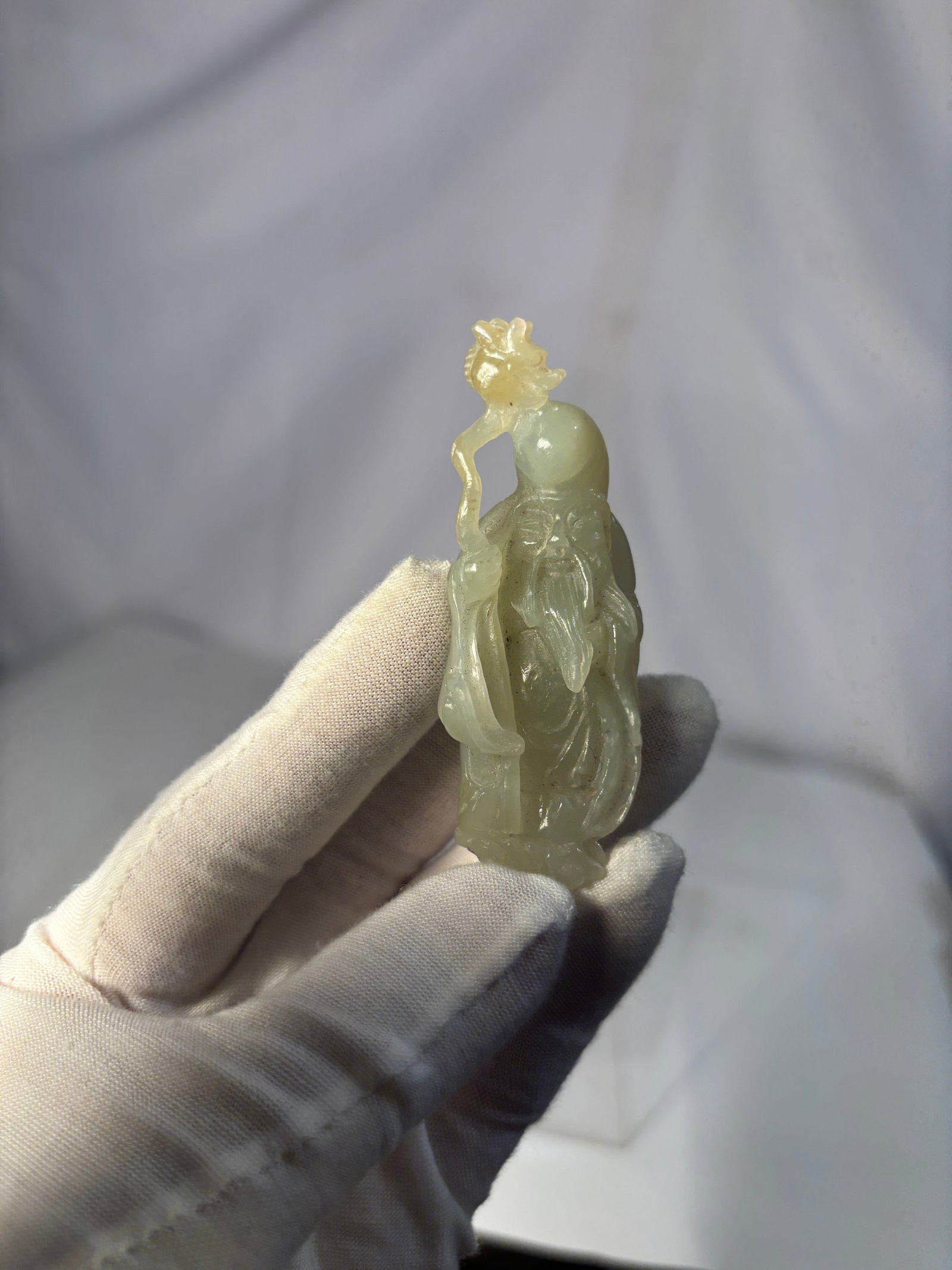 A Chinese Carved Jade Figure of Shouxing with Dragon Staff: A finely carved Chinese figural Statue depicting Shouxing (the God of Longevity), shown with a high domed forehead, long flowing beard, and holding a dragon-headed staff with a gourd suspended from it