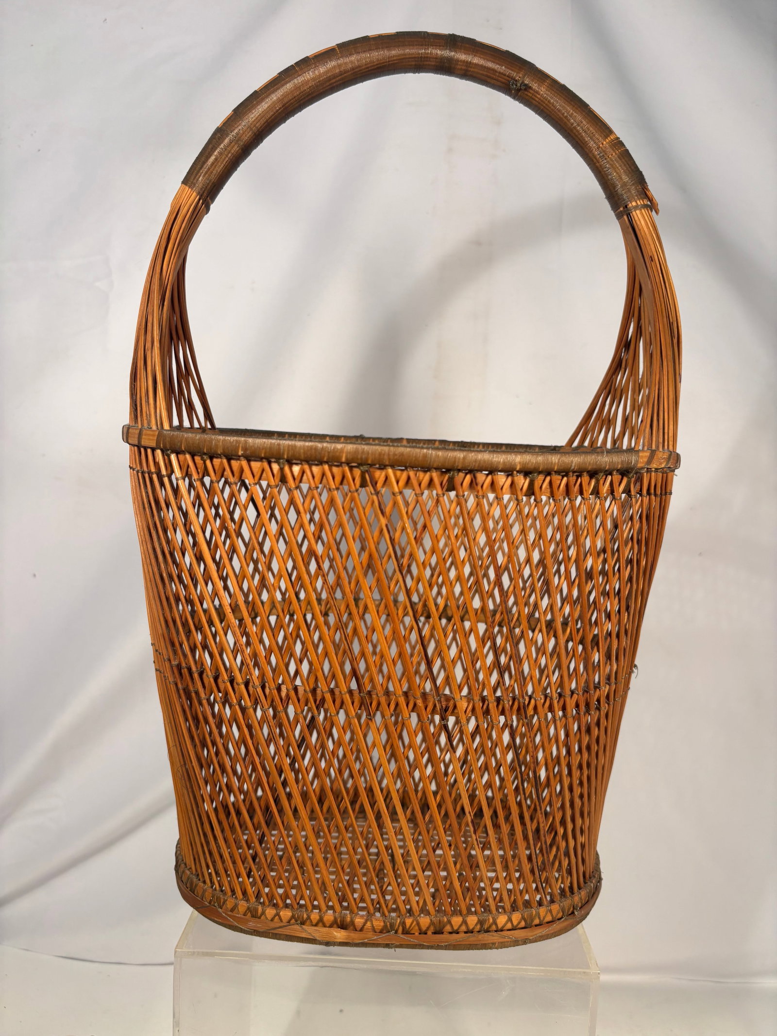 Japanese Meiji Period Woven Bamboo Ikebana Basket: An antique Japanese hanakago flower-arranging basket dating to the Meiji period (1868–1912). The tall oval body features finely executed open diamond-lattice weaving with a reinforced rim and an ele