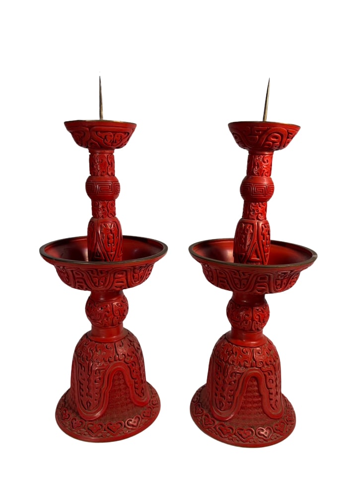 Pair of Chinese Red Lacquer-Style Archaistic Pricket Candlesticks: A decorative pair of Chinese pricket candlesticks finished in deep red lacquer, each featuring a tall tiered standard fitted with two candle spikes and a broad circular drip pan. The surfaces are rich